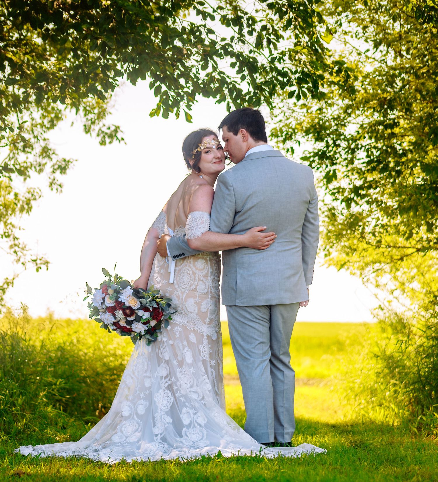 Newlyweds share an intimate moment on a grassy hill during golden hour.