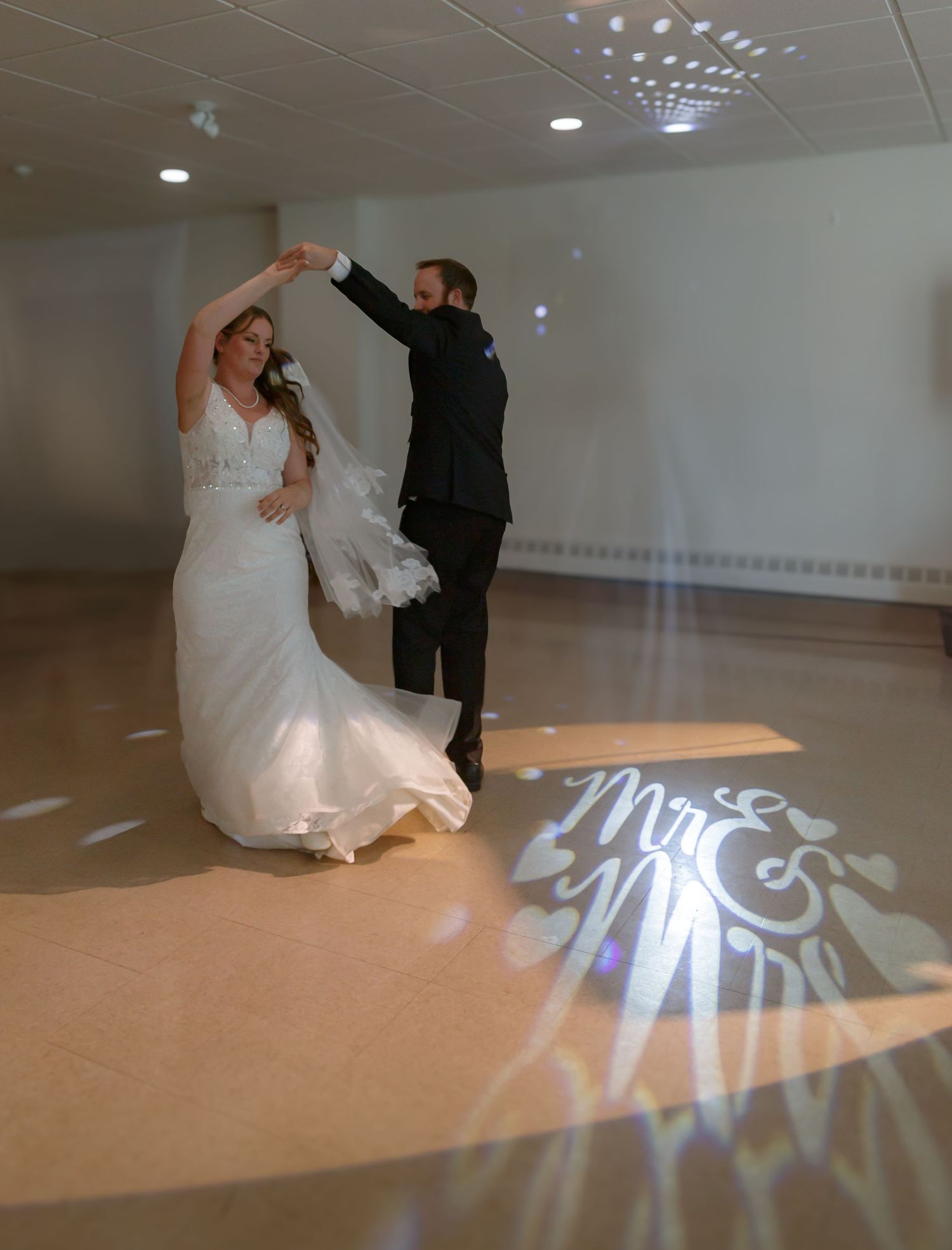Wedding couple dancing under disco lights with Mr & Mrs projection on floor.