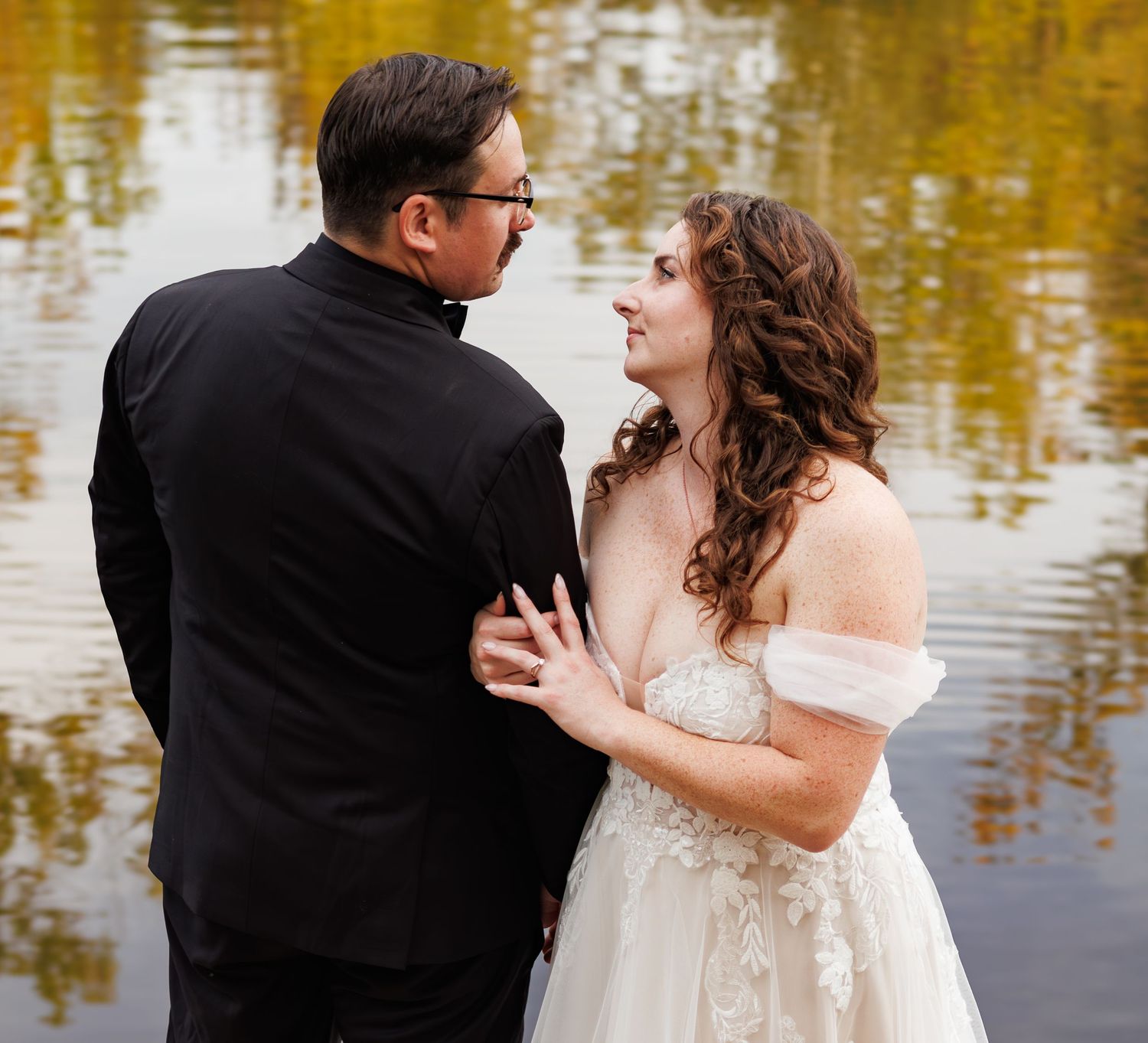 A romantic dance sequence by a lake with golden reflections in the water.