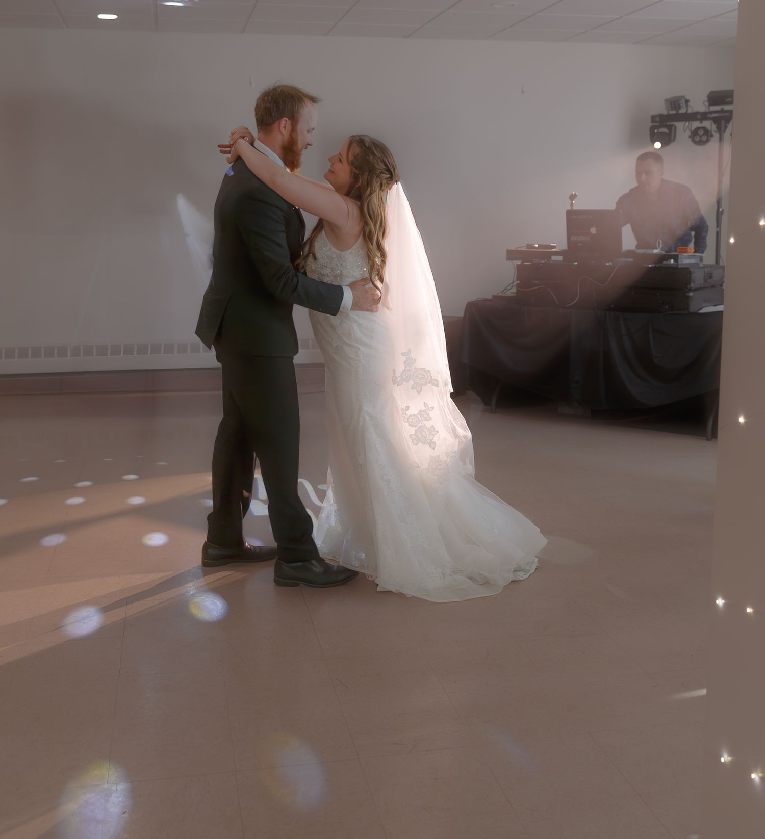 Couple sharing their first dance at wedding reception with soft lighting effects.