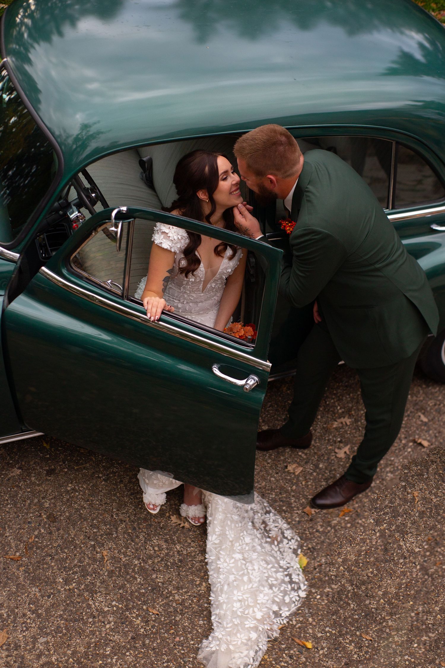 Romantic moment with classic green vintage car during wedding photoshoot.