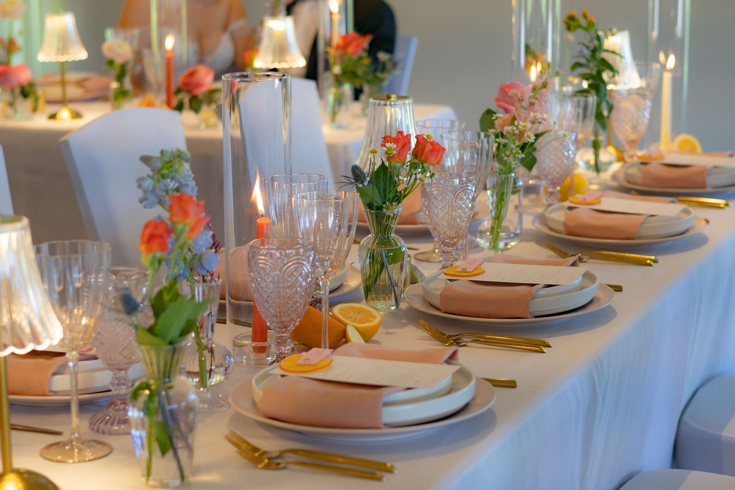 Elegant wedding reception table set with pink floral centerpieces and fine china.