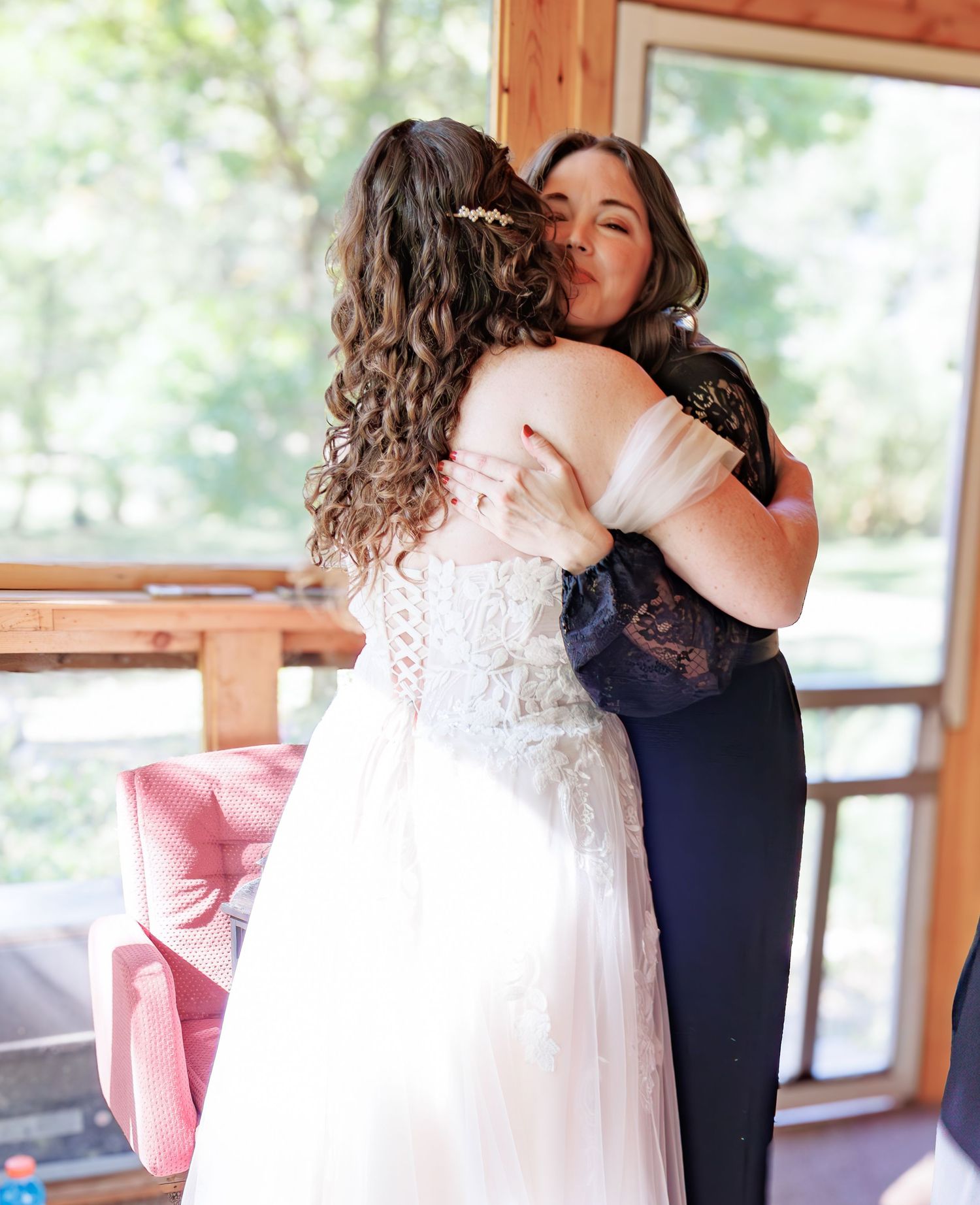 Two people share emotional embrace in white and navy formal attire.