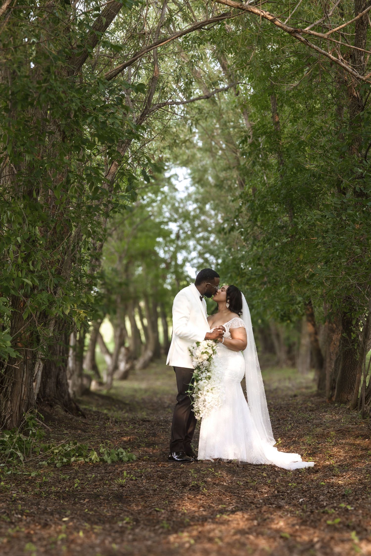 A wedding couple shares intimate moments in a wooded area during their photoshoot.