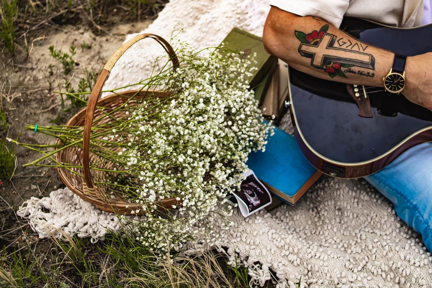 A romantic picnic setting with baby's breath flowers in a basket and a guitar on a blanket.