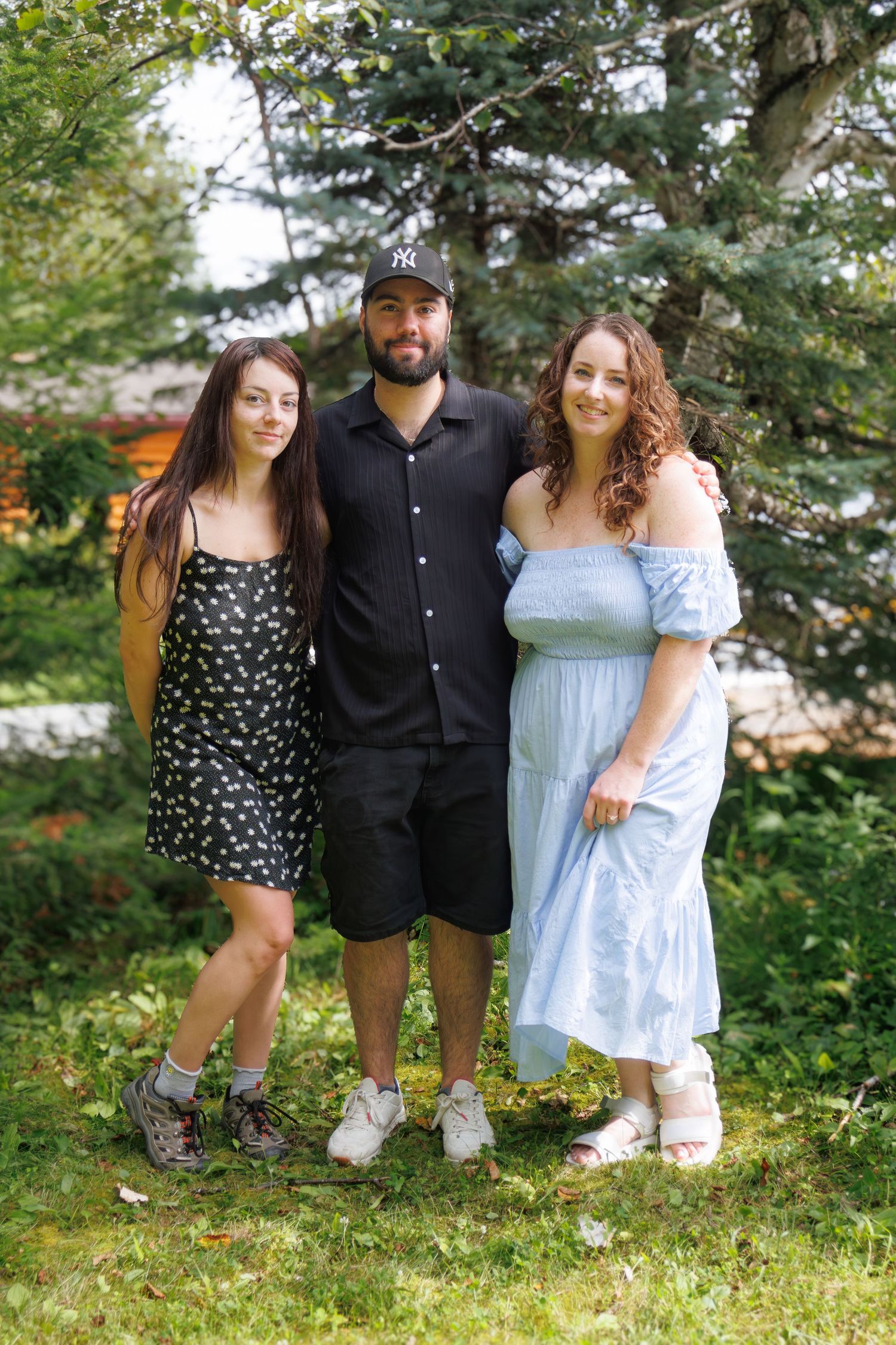 Family group poses together on grass in casual summer outfits.