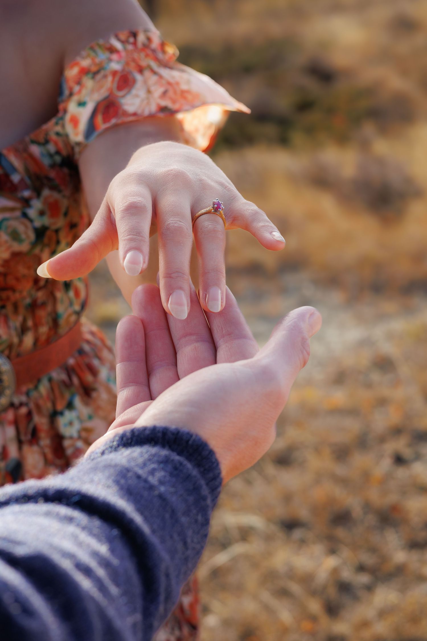 Close-up sequence of hands displaying an engagement ring against a desert backdrop.