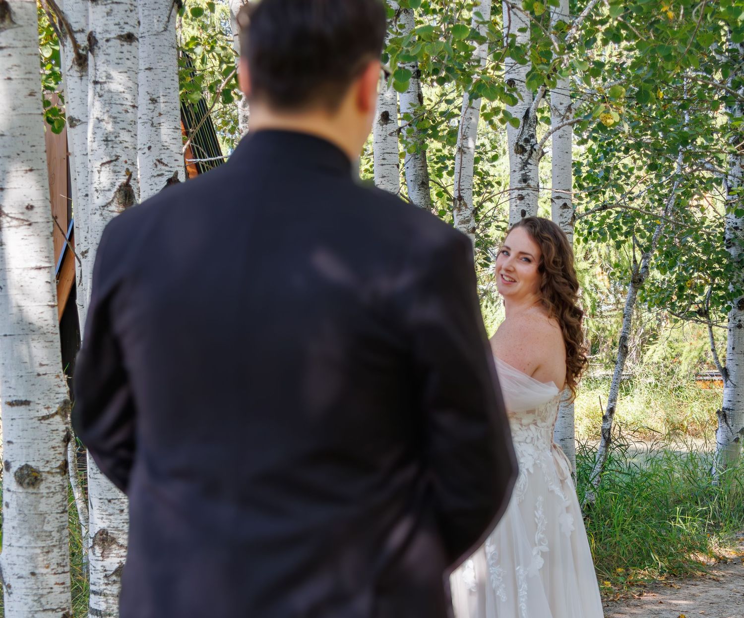 A couple poses for romantic wedding photos among white birch trees in a natural outdoor setting.