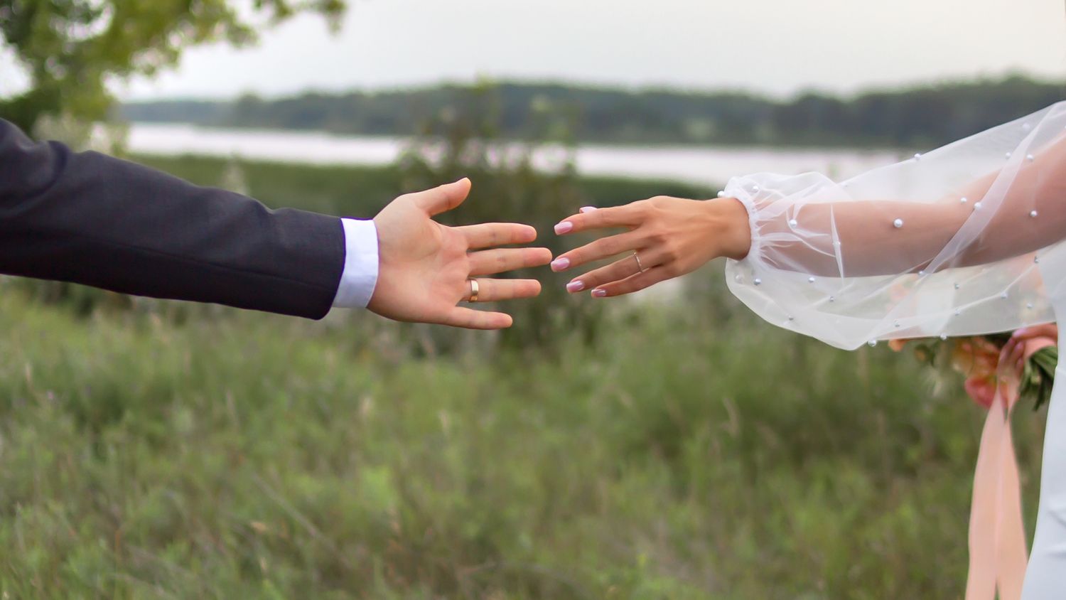 Close-up of hands reaching towards each other in outdoor setting.