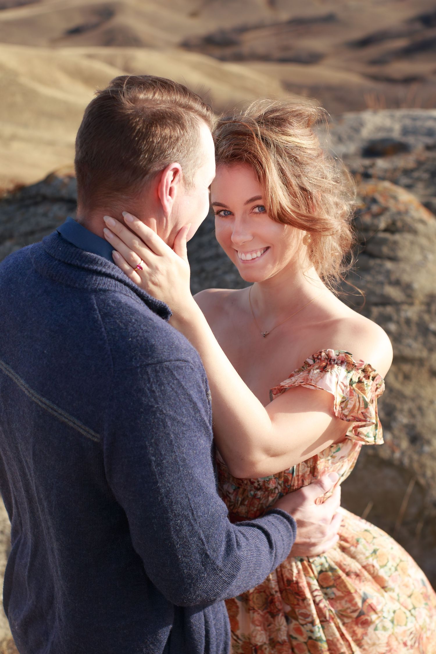 Intimate moment shared between couple on rocky terrain during golden hour.