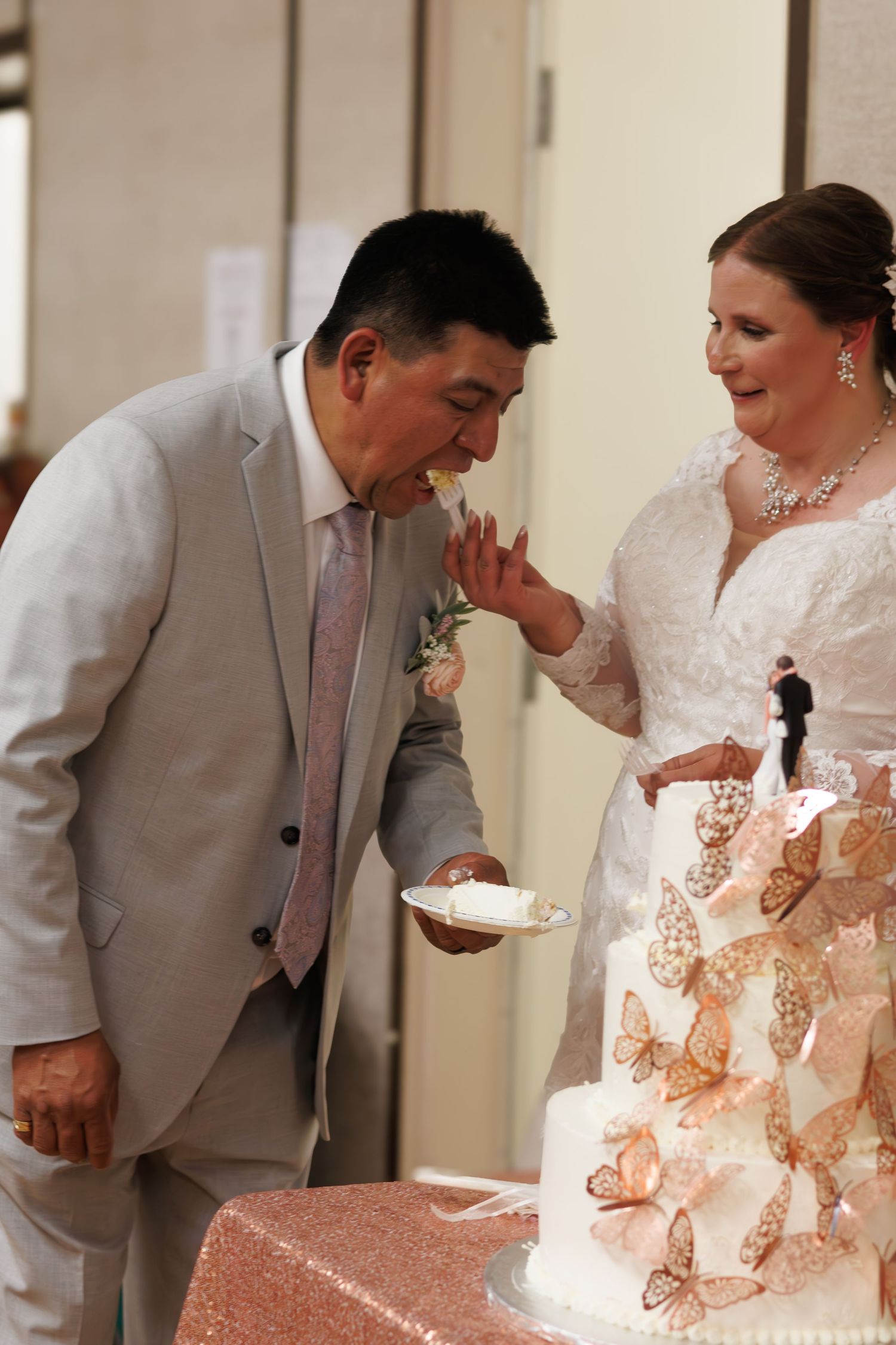 Wedding couple sharing an intimate moment with their wedding cake decorated with butterflies.