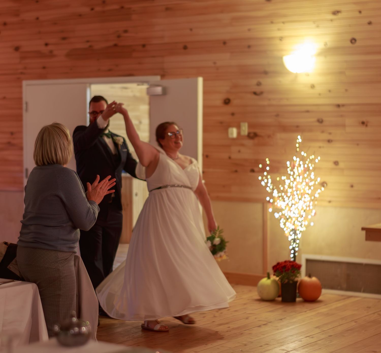 Wedding reception in a rustic wood-paneled venue with warm lighting and decorative elements.