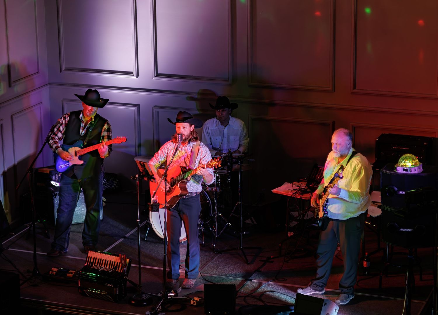 Band performs on stage with colorful lighting and classic country western attire.