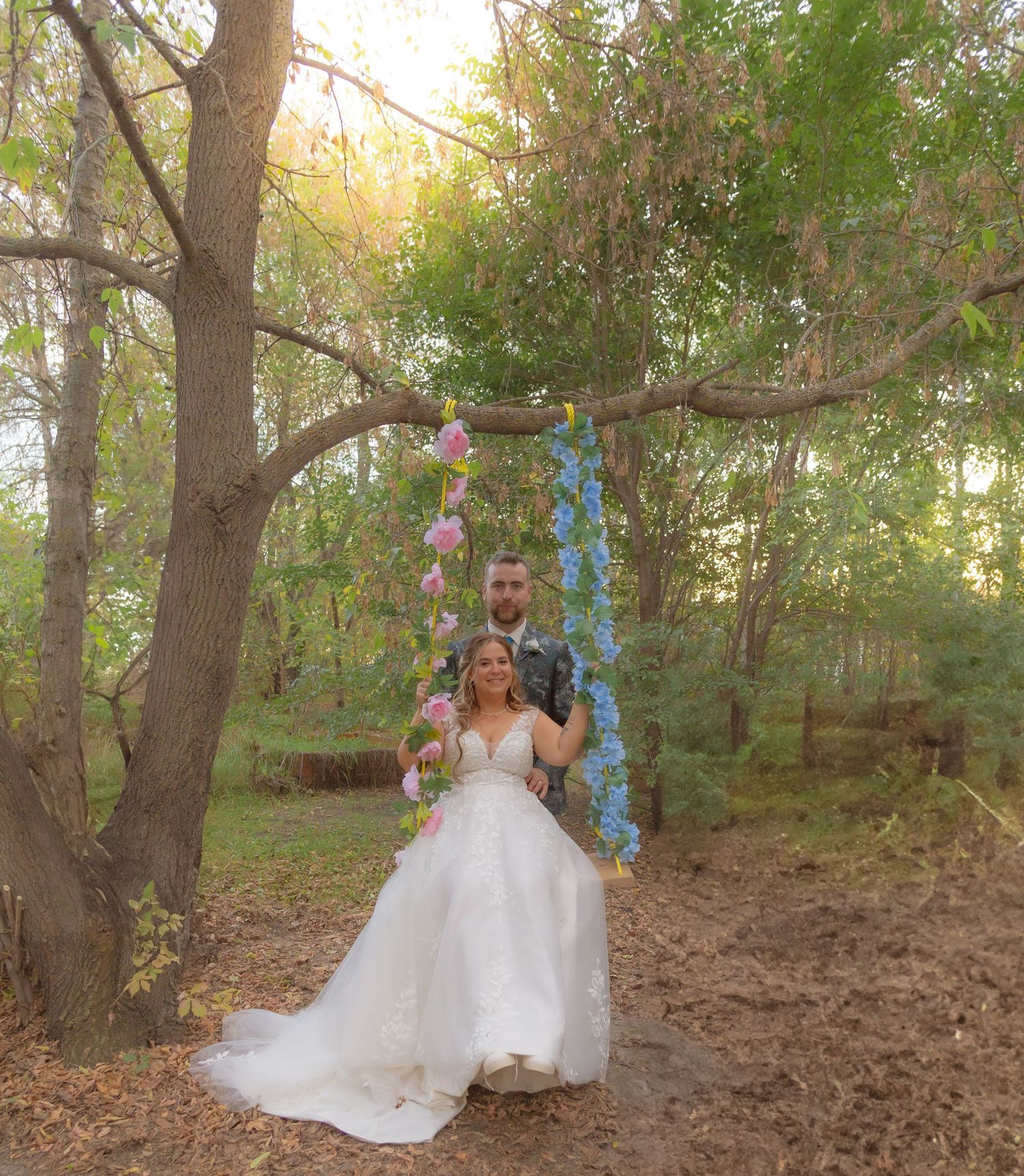 Wedding photo session in a wooded area with hanging blue decorations.