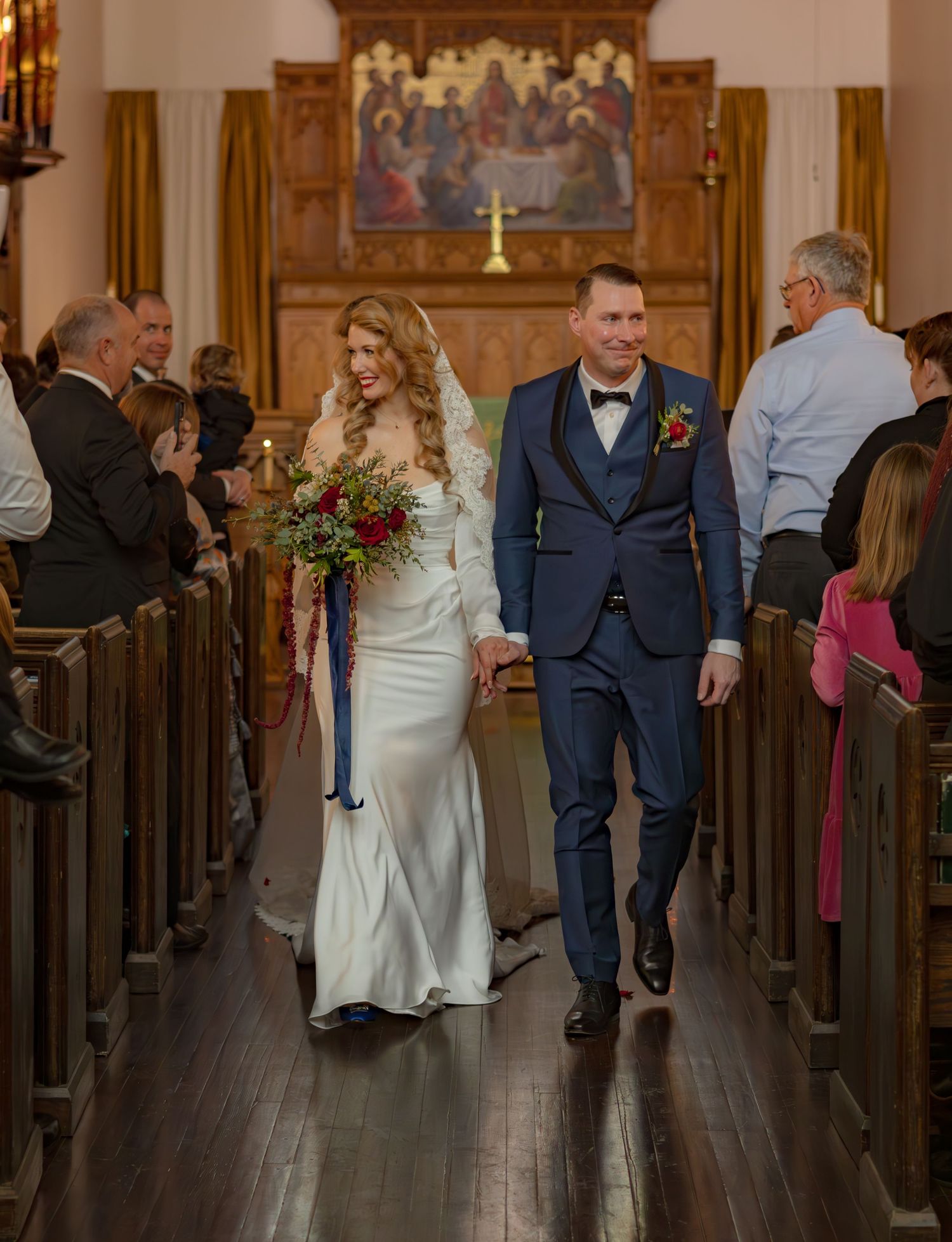 Wedding ceremony exit in a traditional wooden church with guests lining the pews.