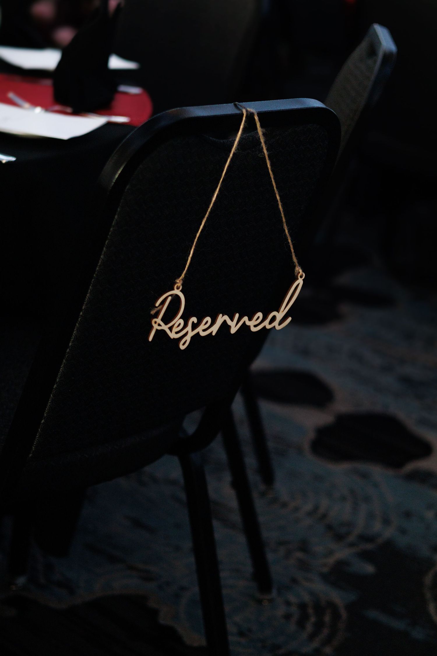 Gold 'Reserved' sign hanging on black chair at formal event.
