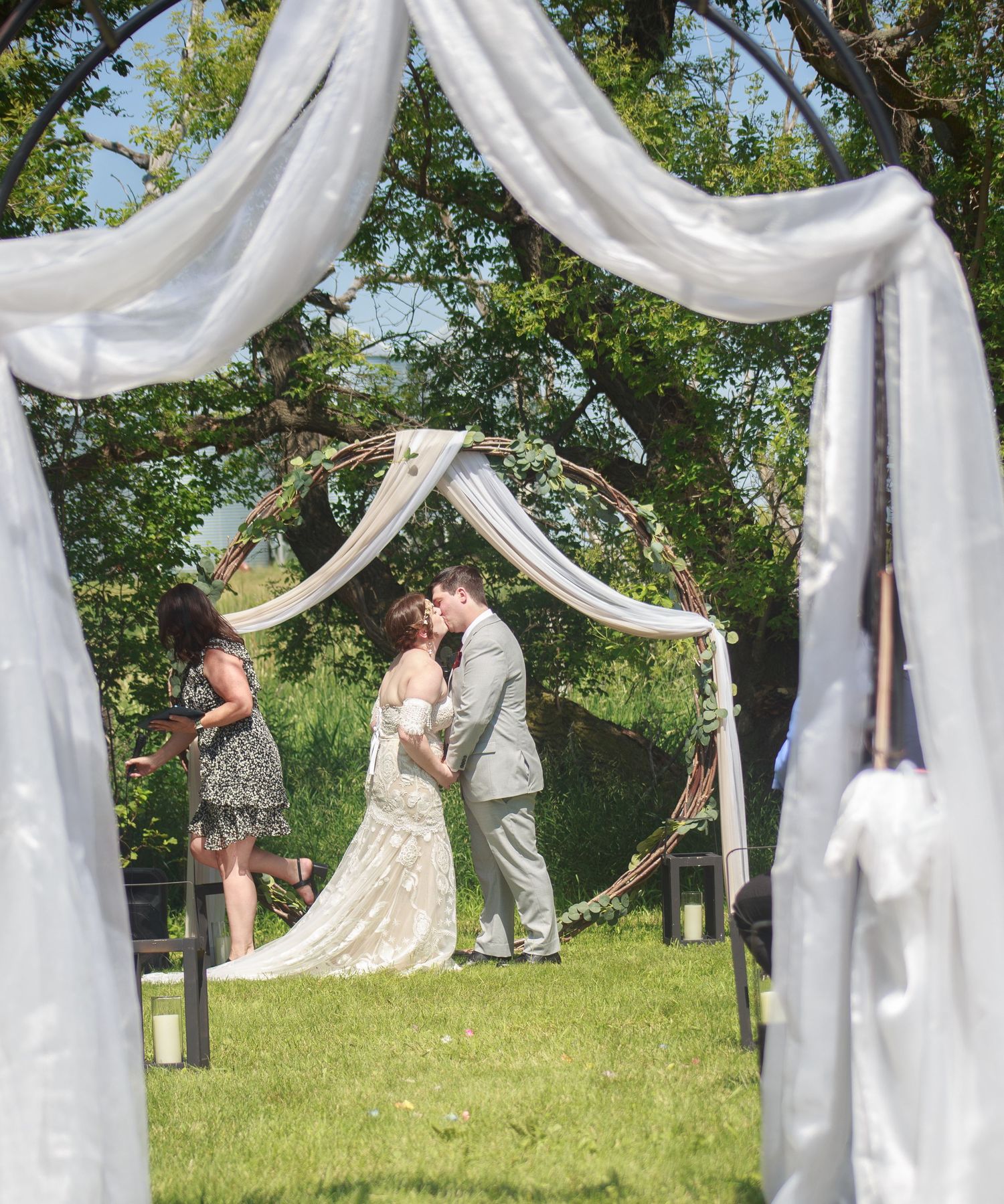 Wedding ceremony setup outdoors with flowing white fabric draped between trees.