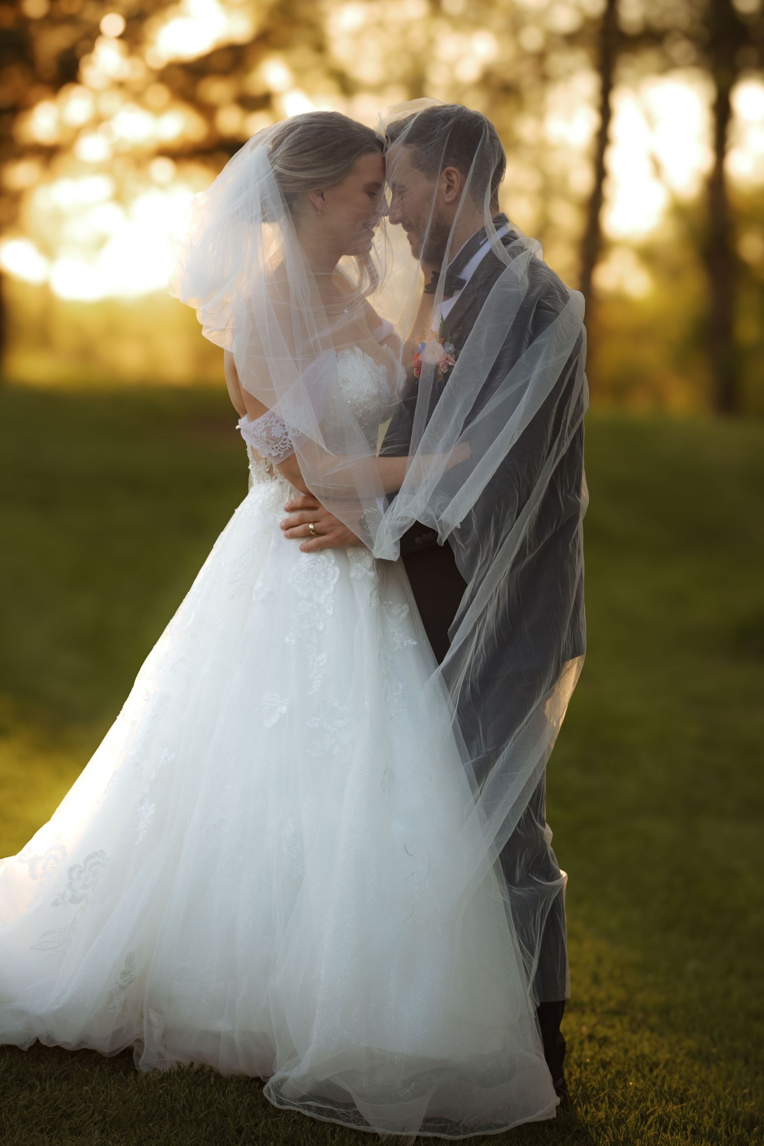 Romantic wedding couple embracing in a sunlit meadow during golden hour.