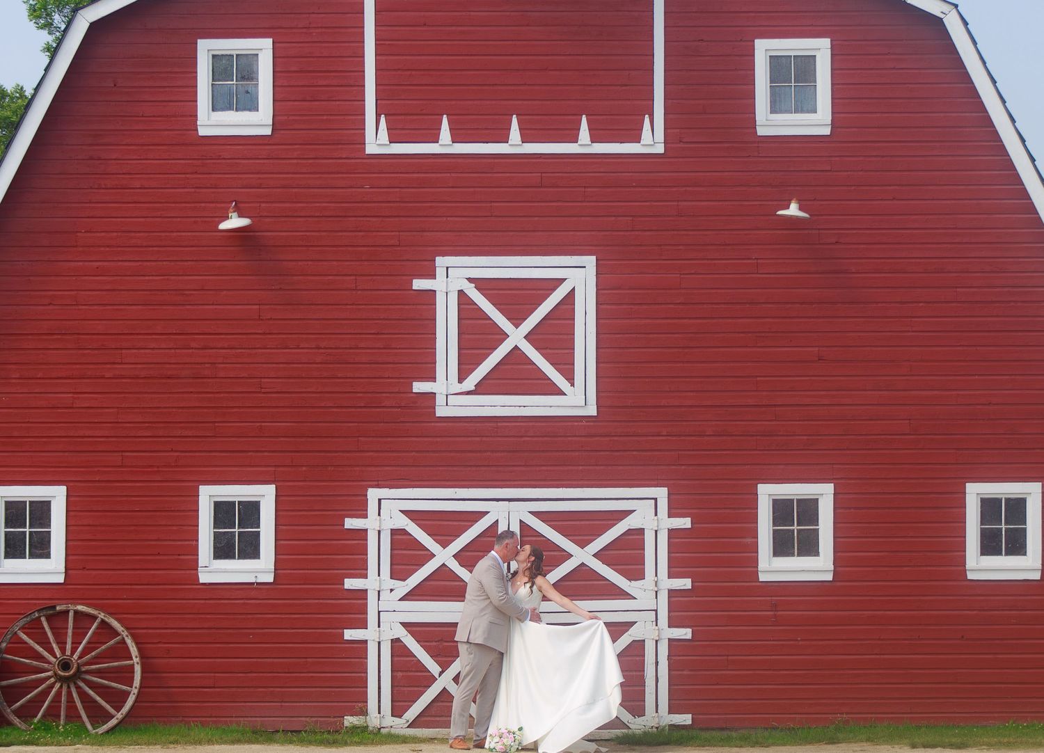 Classic red barn with white trim and traditional architectural details against blue sky.