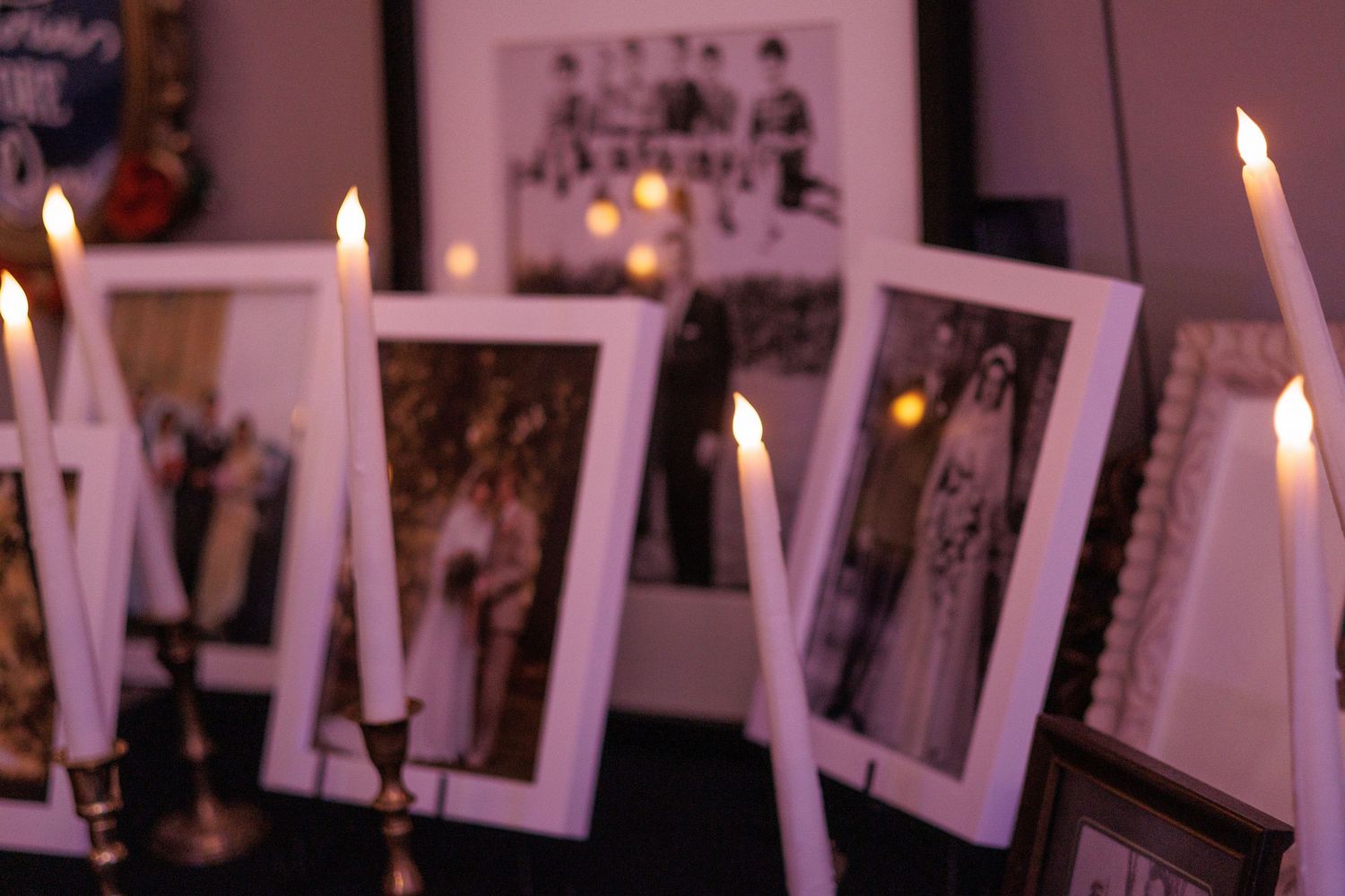 Candlelit wedding reception detail with framed photos creating romantic ambiance.
