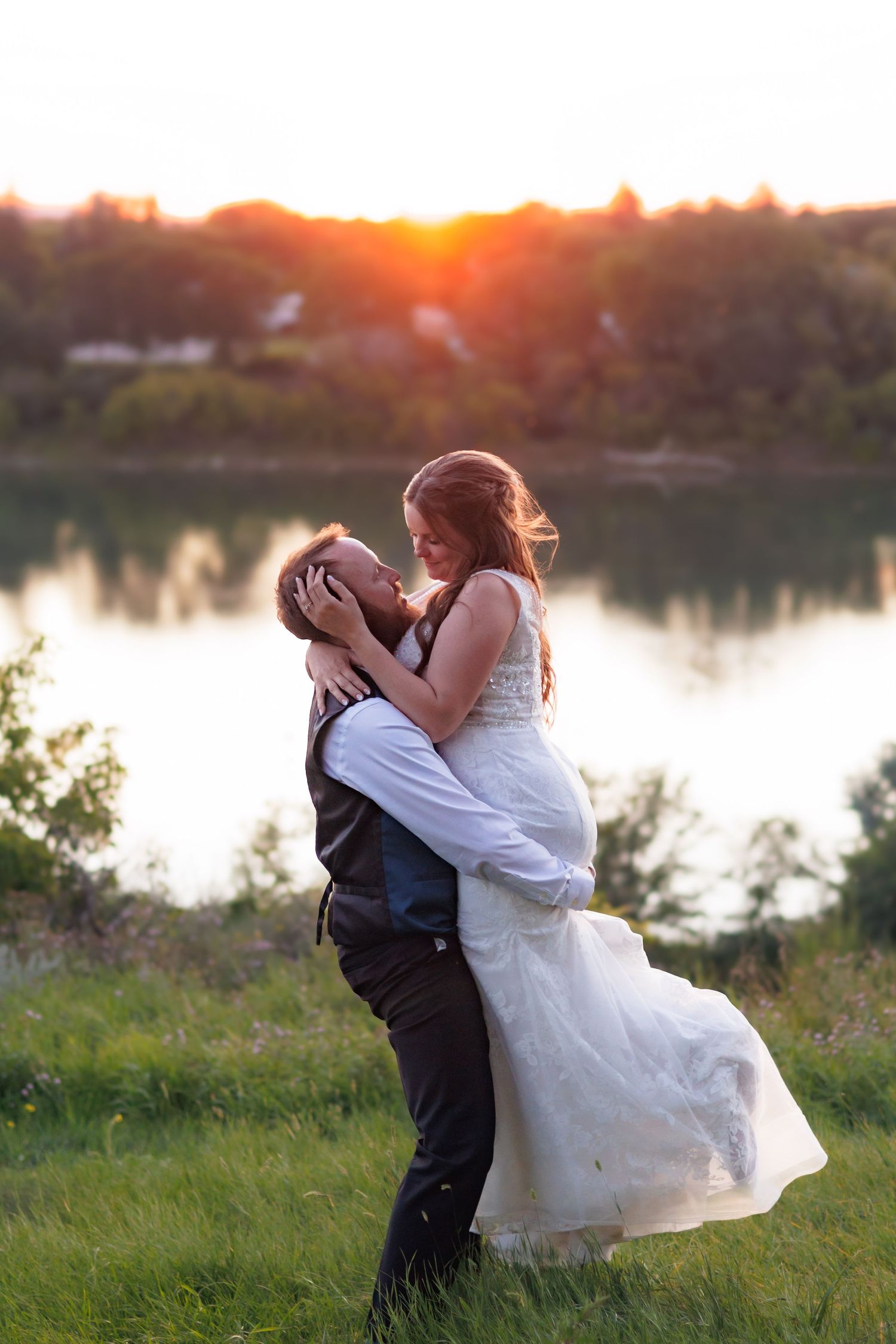 Sunset wedding portraits by a serene lake with dramatic lighting.