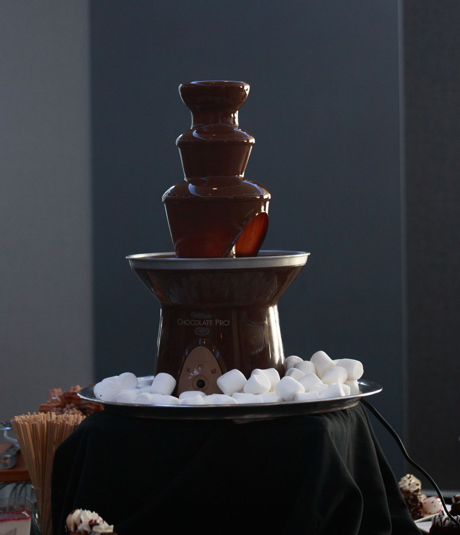 Chocolate fountain display with marshmallows on a tiered stand.