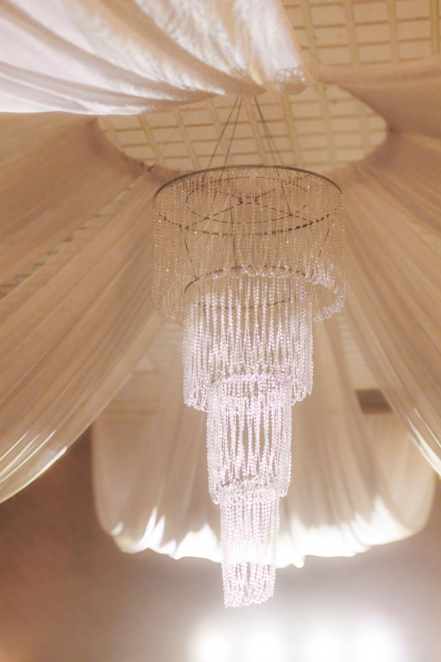 Crystal chandeliers hanging from draped white fabric ceiling creating an elegant ambiance.