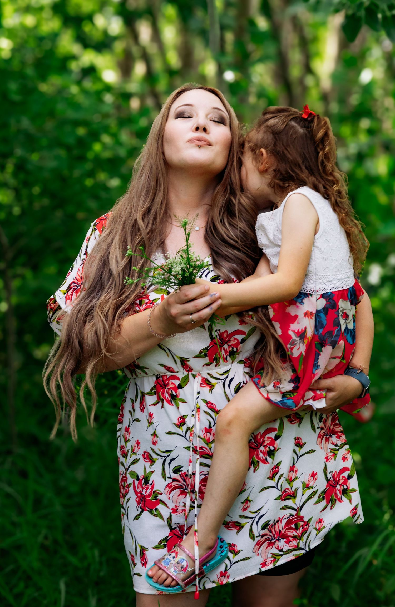 Two people in matching floral dresses playing together in a lush green outdoor setting.