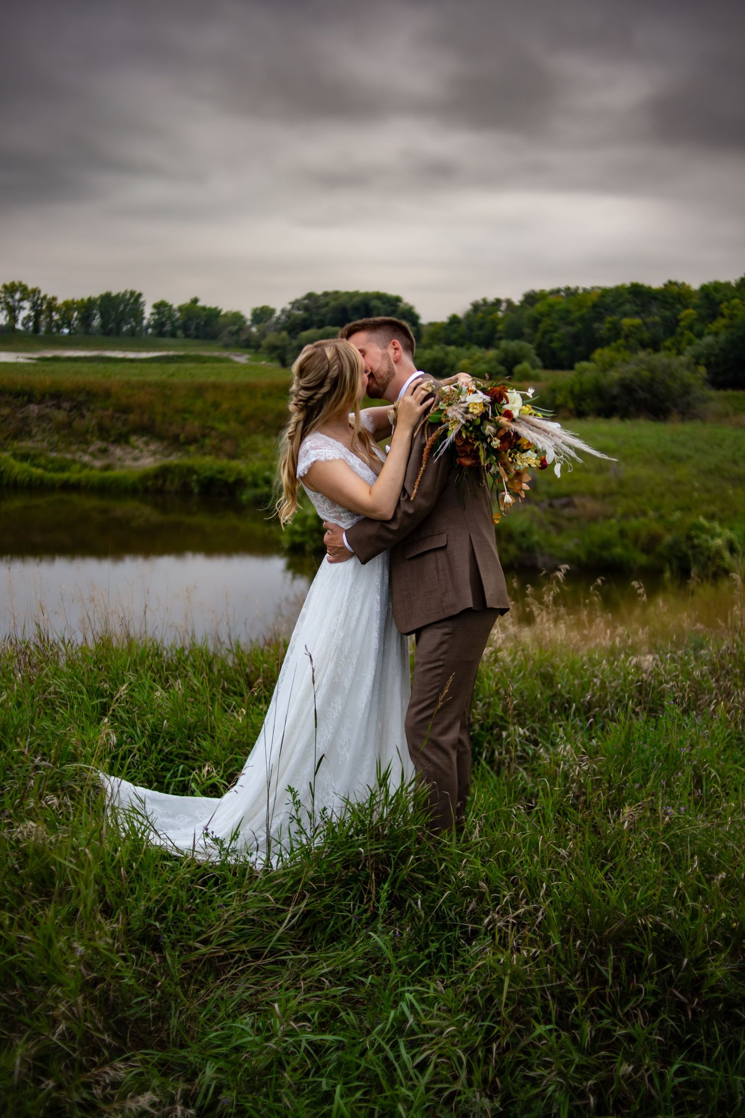 Romantic wedding photos captured in a scenic meadow near a lake.