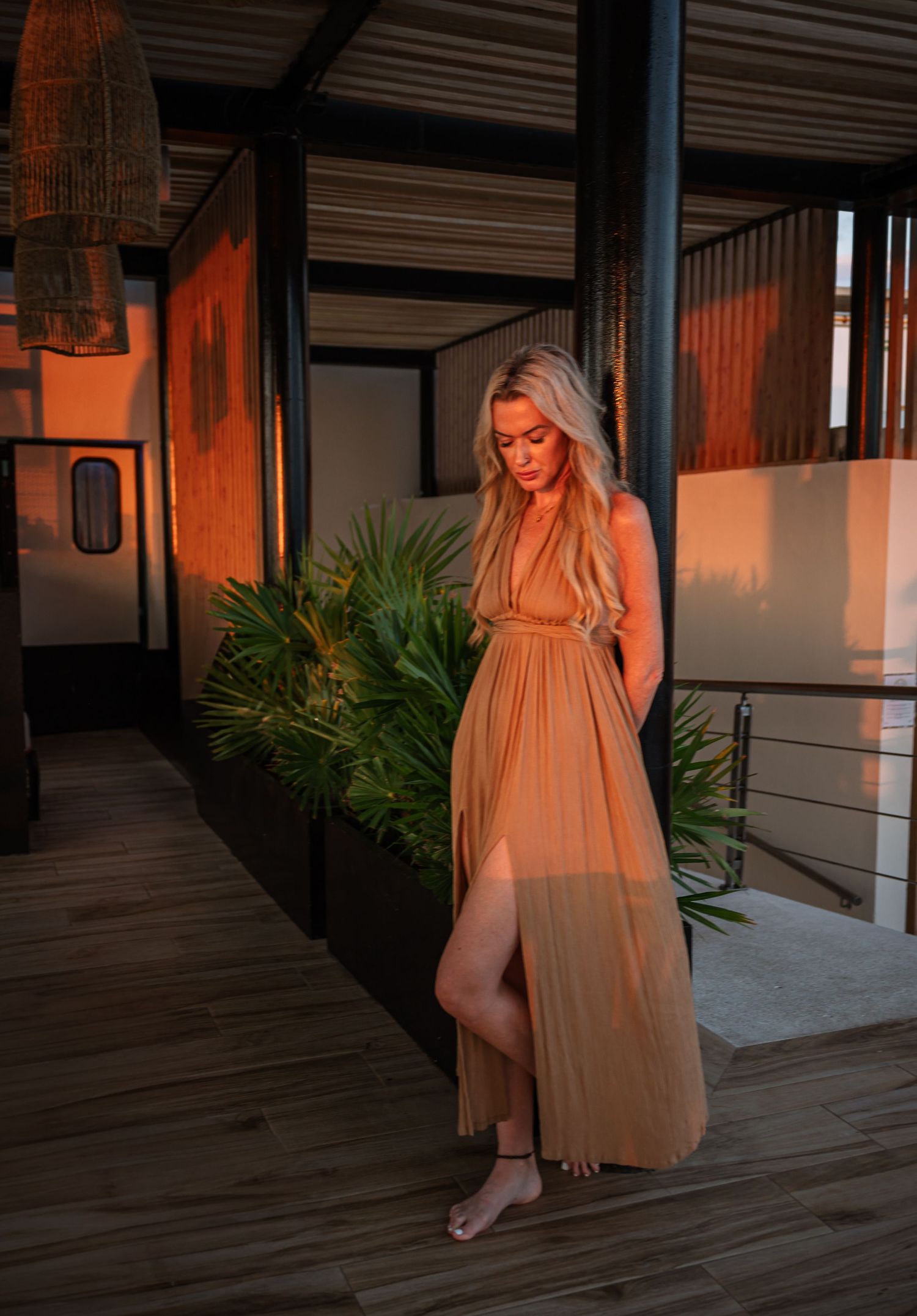 Warm sunset lighting on wooden deck with tropical plants and modern architecture.
