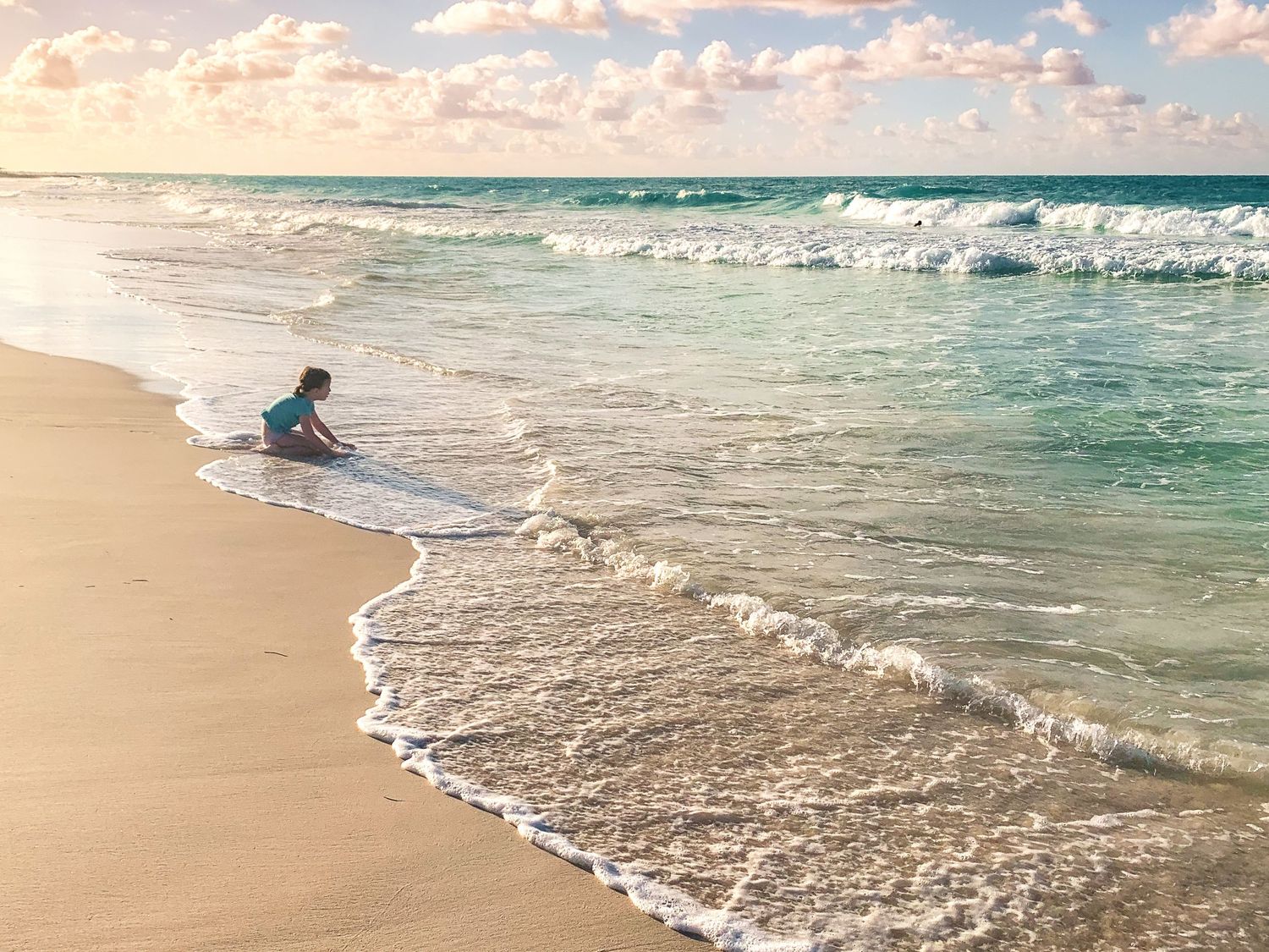 A serene beach scene with gentle waves rolling onto shore during golden hour.