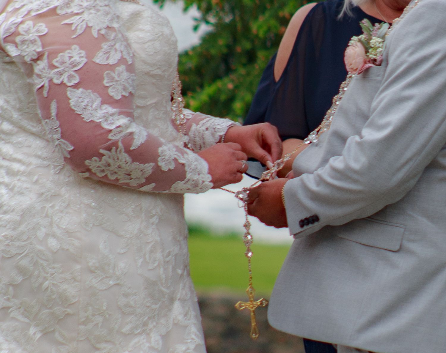 Detailed view of hands holding a decorative rosary during a wedding ceremony.