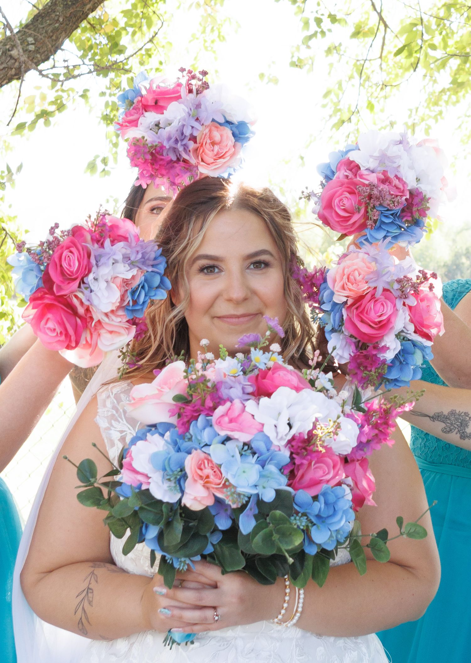 Vibrant pink and blue wedding bouquet with roses and mixed flowers against natural backdrop.
