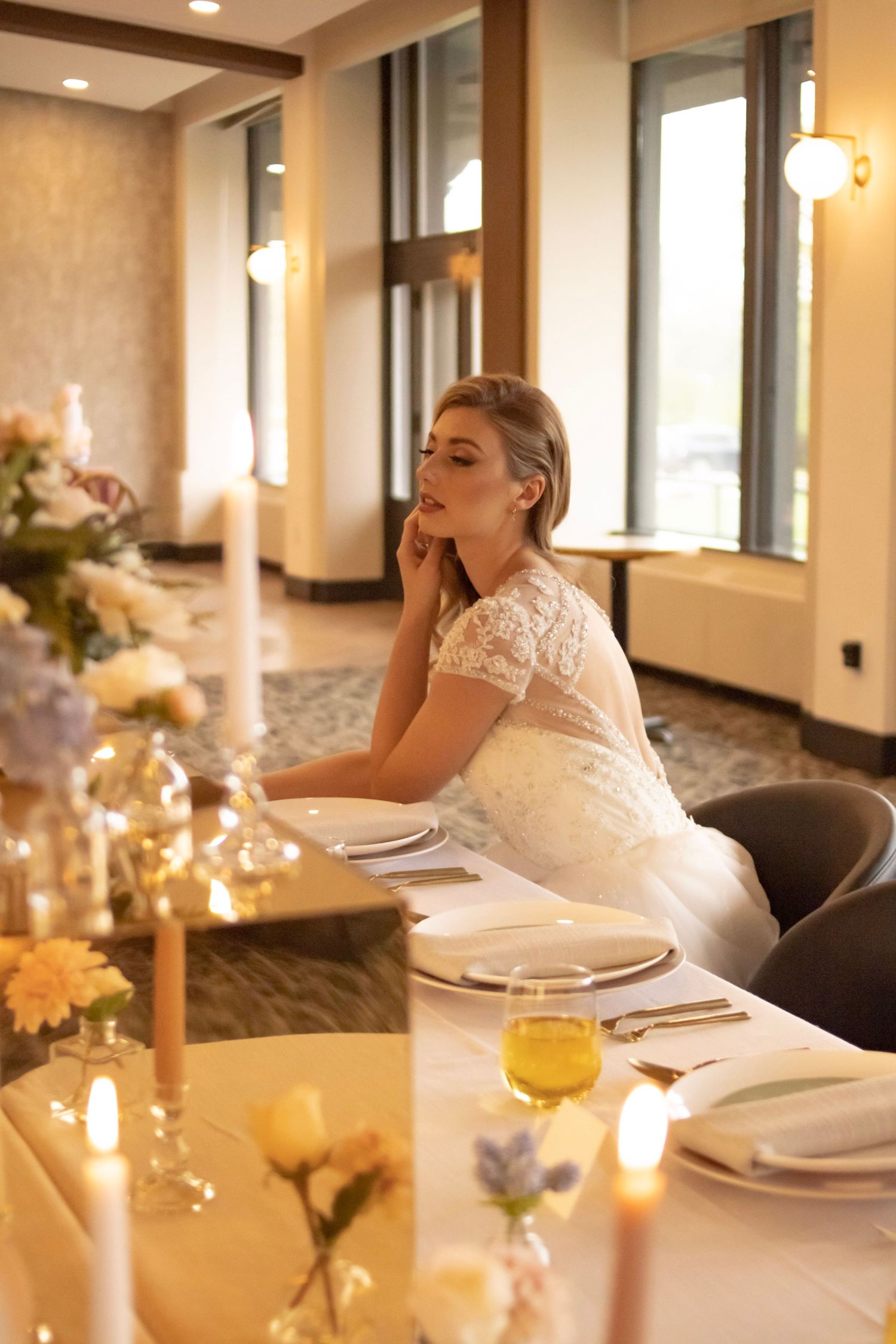 Elegant wedding reception table setting with candles and place settings in warm lighting.
