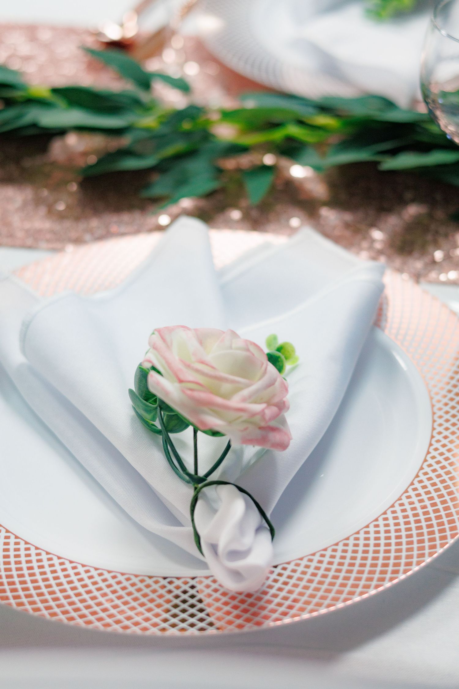 Elegant place setting with pink rose detail and decorative charger plate.