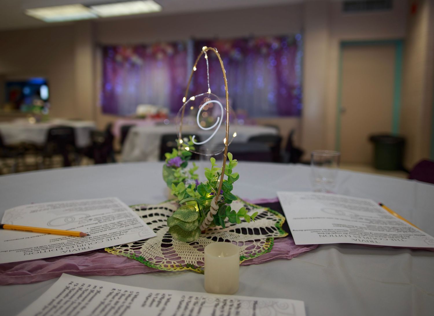 Wedding reception table with purple accents and scattered paper decorations.