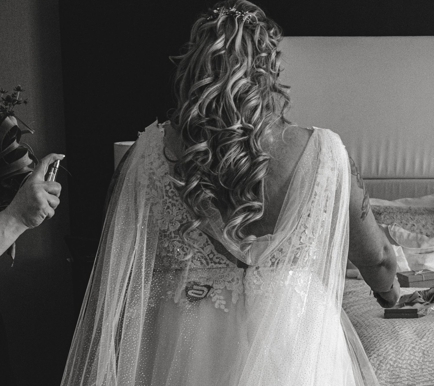 Close-up details of a white lace wedding dress with delicate veil in black and white.