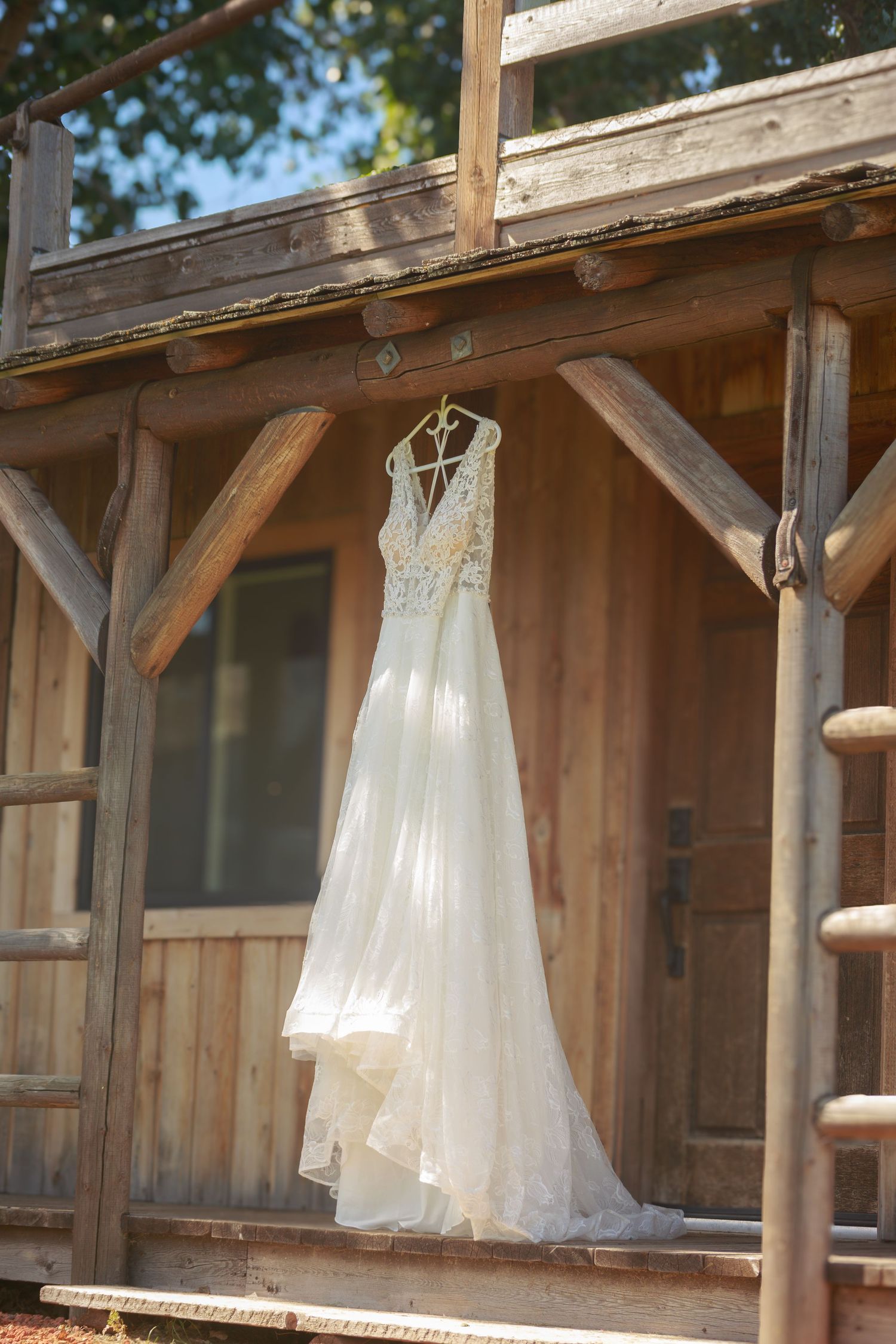 White wedding dresses hanging from wooden beams in a rustic venue.
