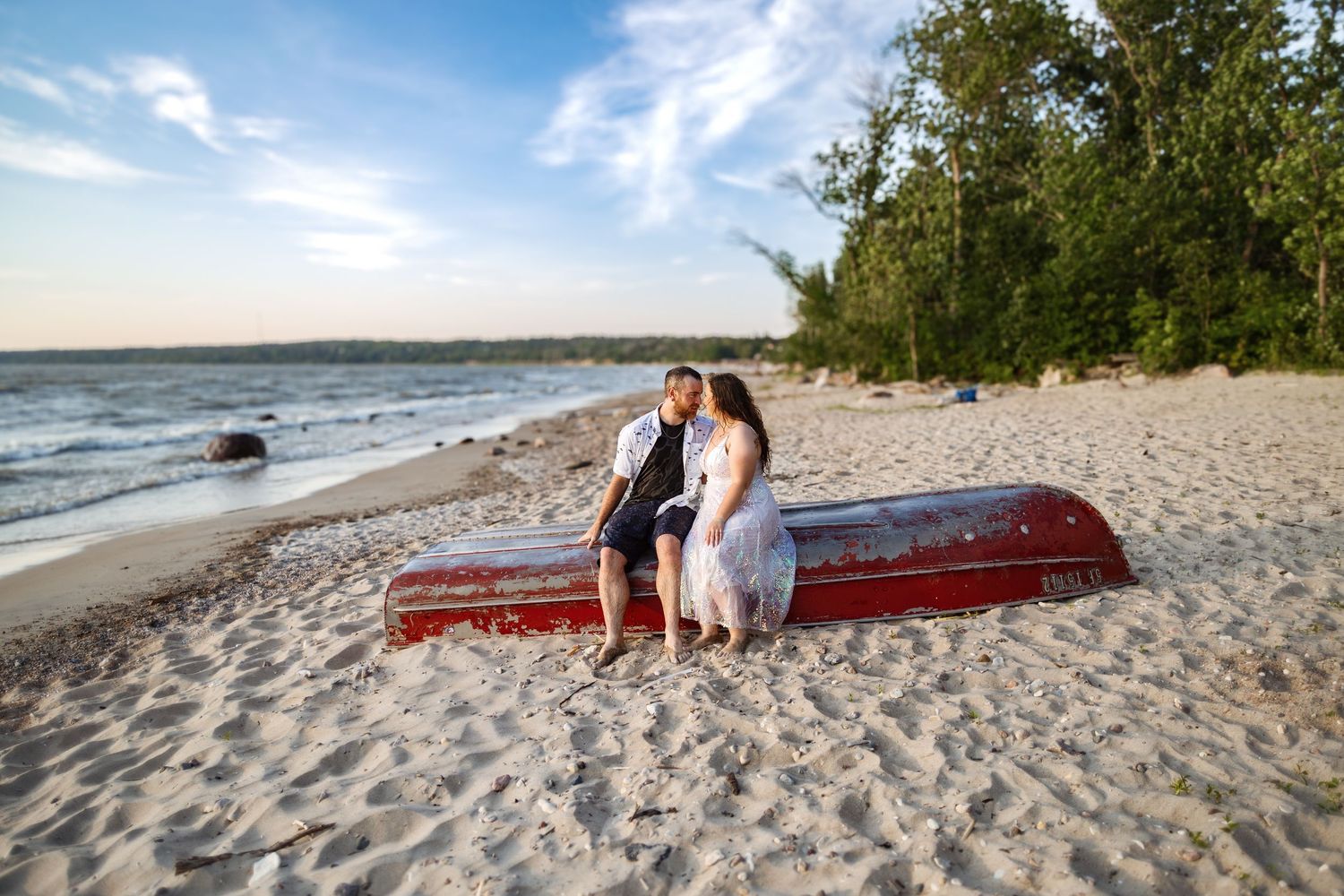 Couple walking along a scenic beach at sunset with waves crashing on the shore.