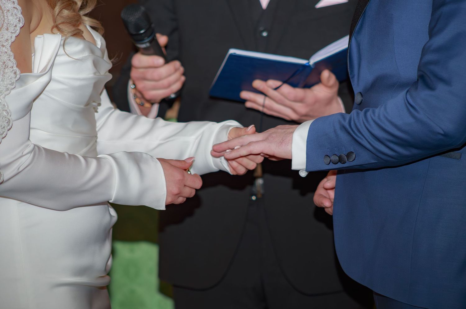 Close-up of hands during wedding ceremony ring exchange.