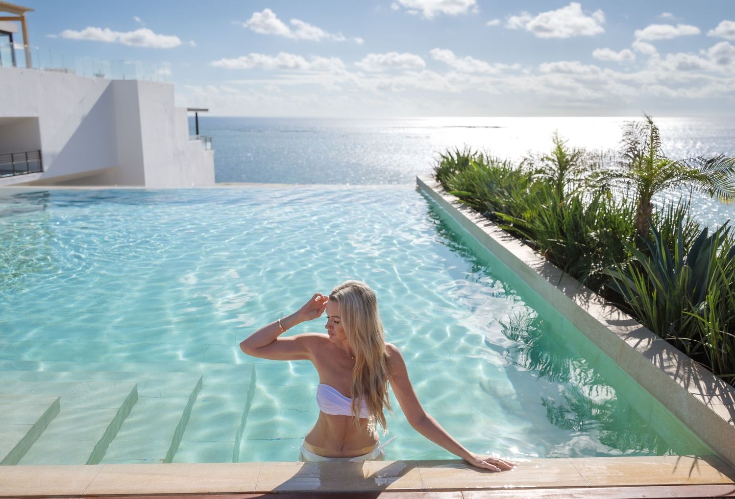 Luxurious rooftop infinity pool merging with ocean horizon on sunny day.