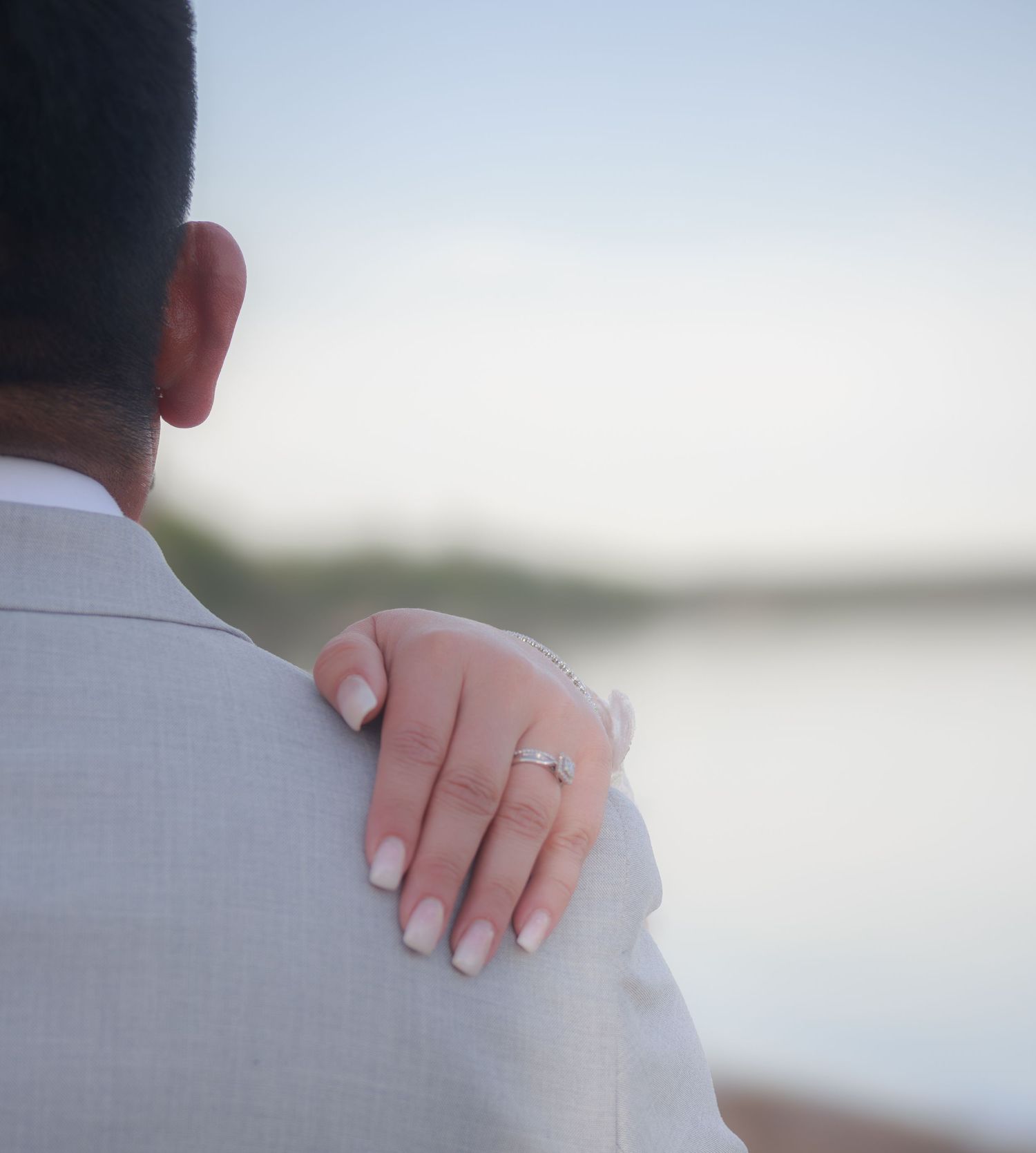 Close-up detail of hands during intimate waterfront wedding moment.