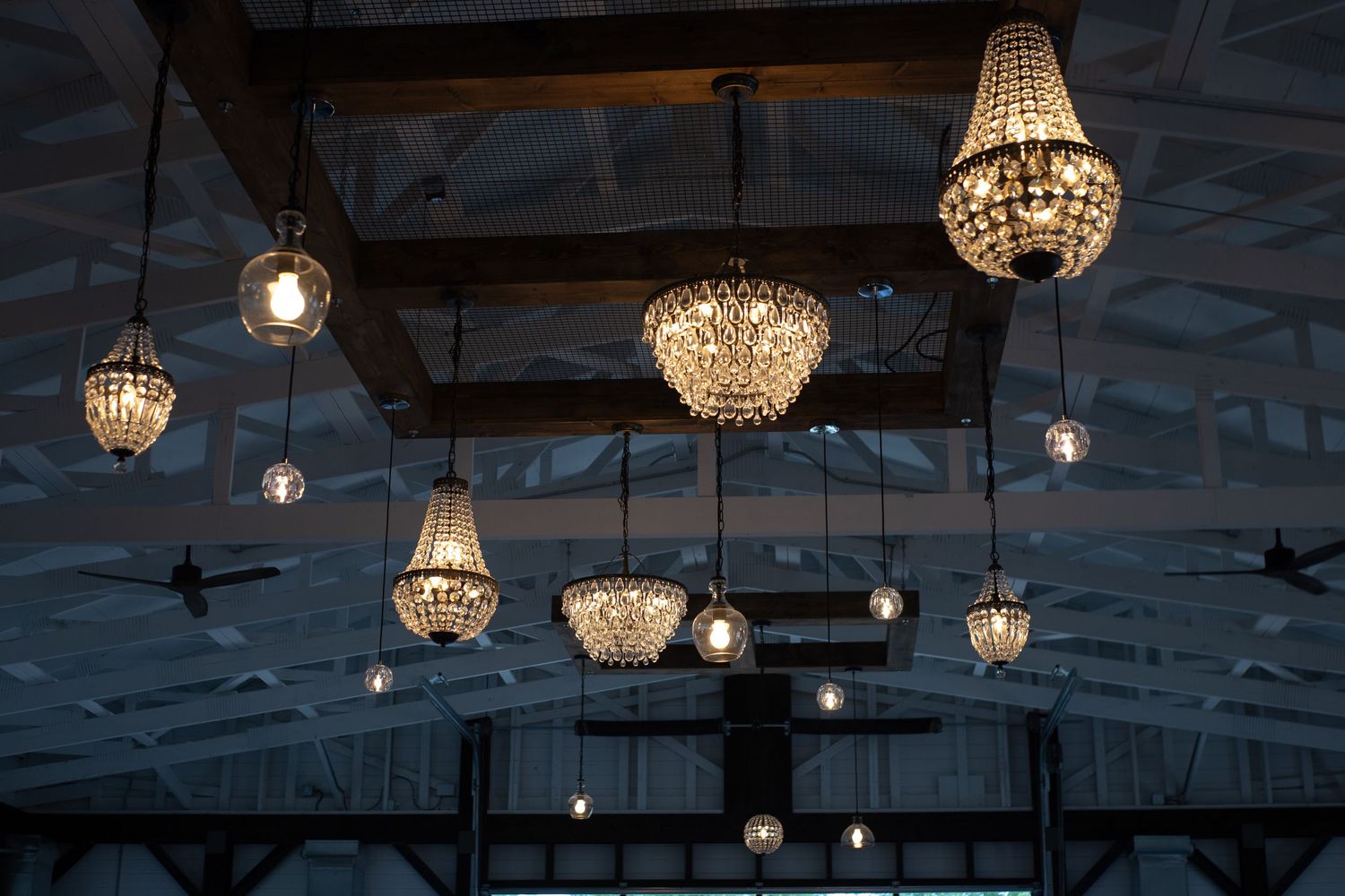 Elegant crystal chandeliers hang from the ceiling creating a romantic ambiance for a wedding venue.