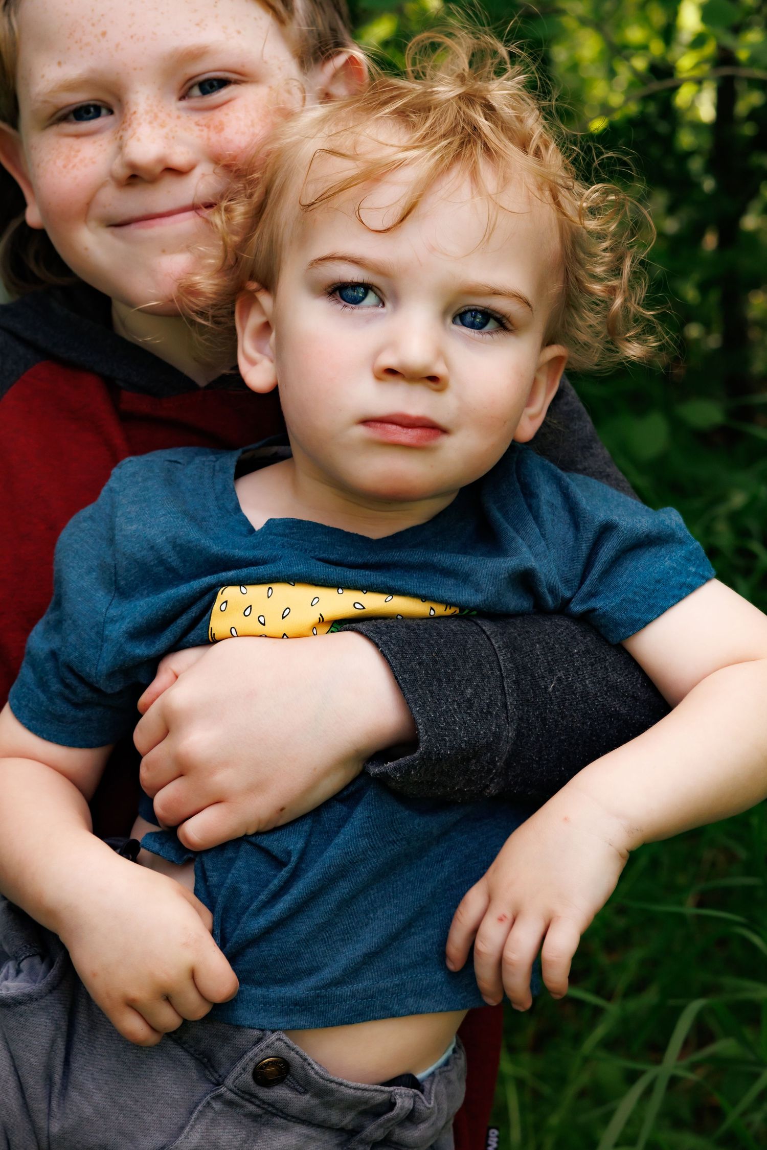 Close-up portrait of young children embracing outdoors.
