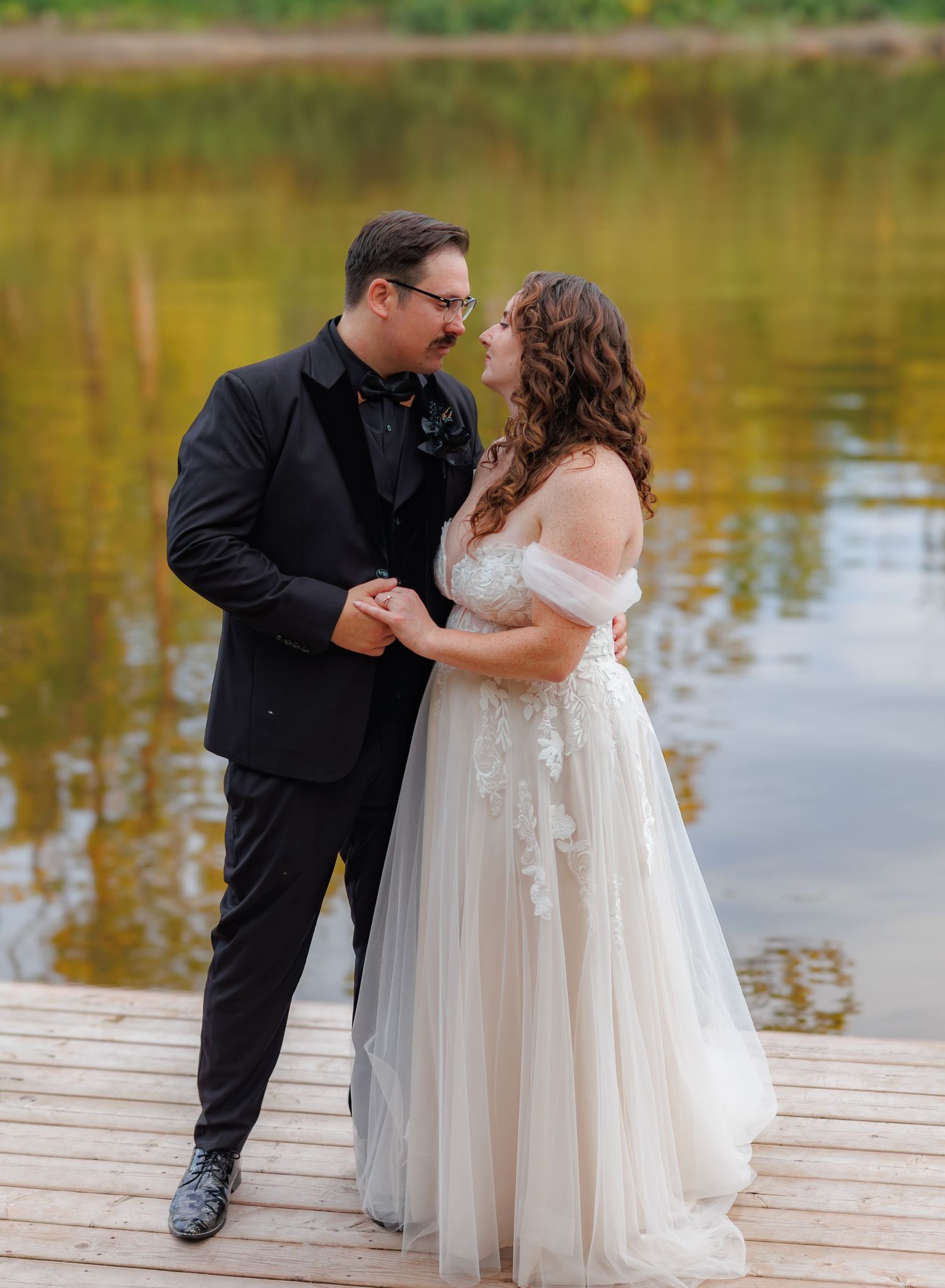 A romantic moment captured on a wooden dock by a lake during sunset.
