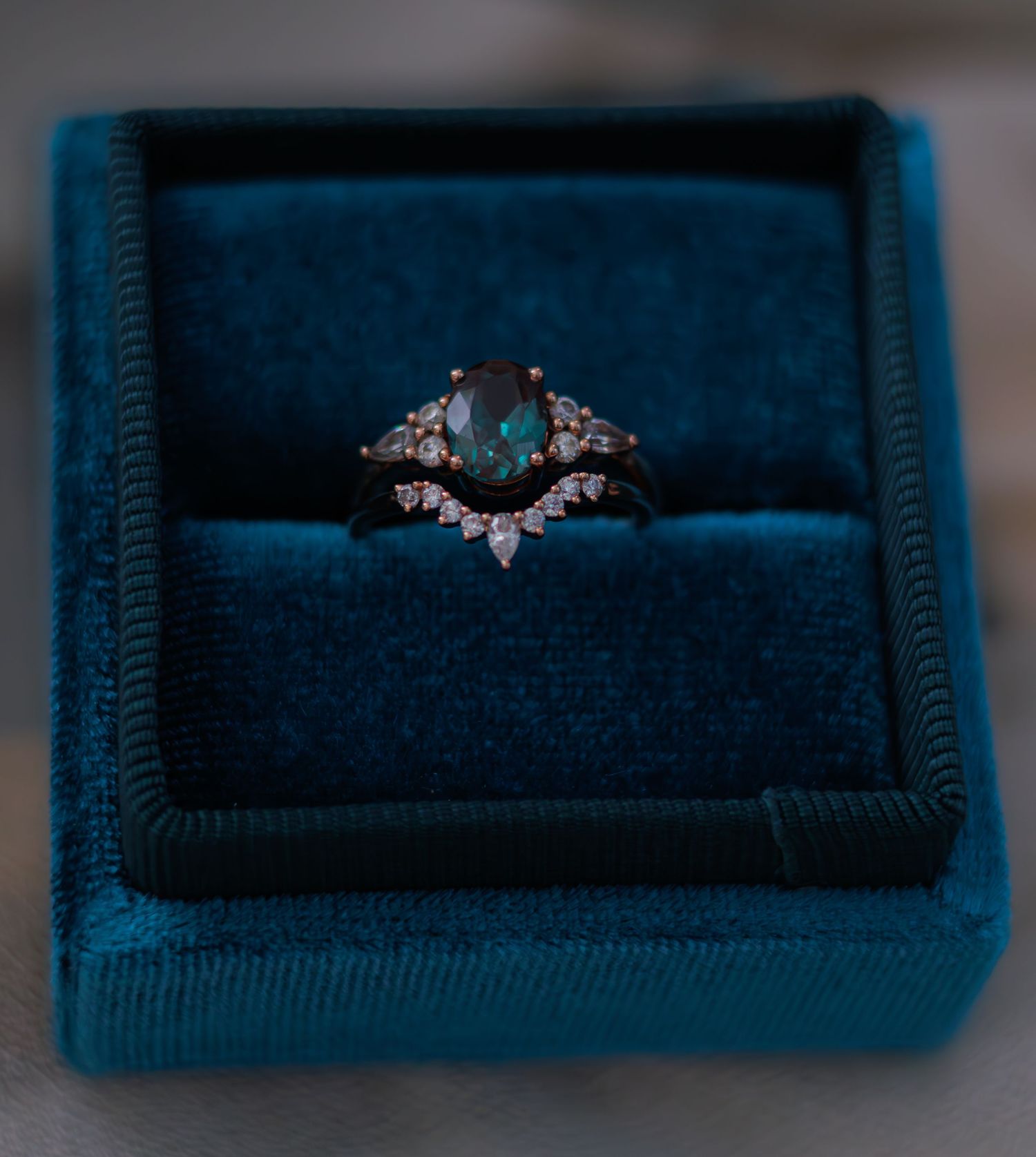 Elegant engagement ring with diamond accents displayed in a navy blue velvet ring box.