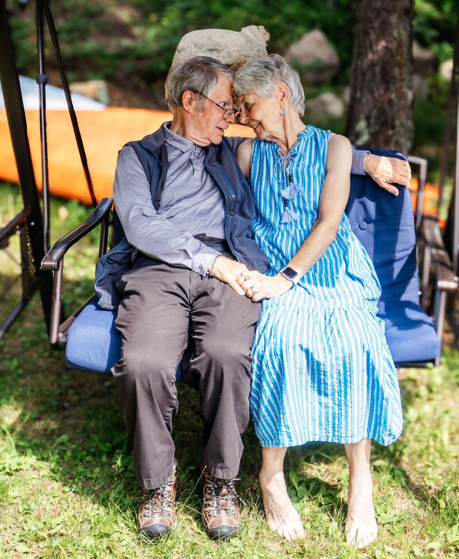 Senior couple sitting on outdoor swing sharing tender moments together.