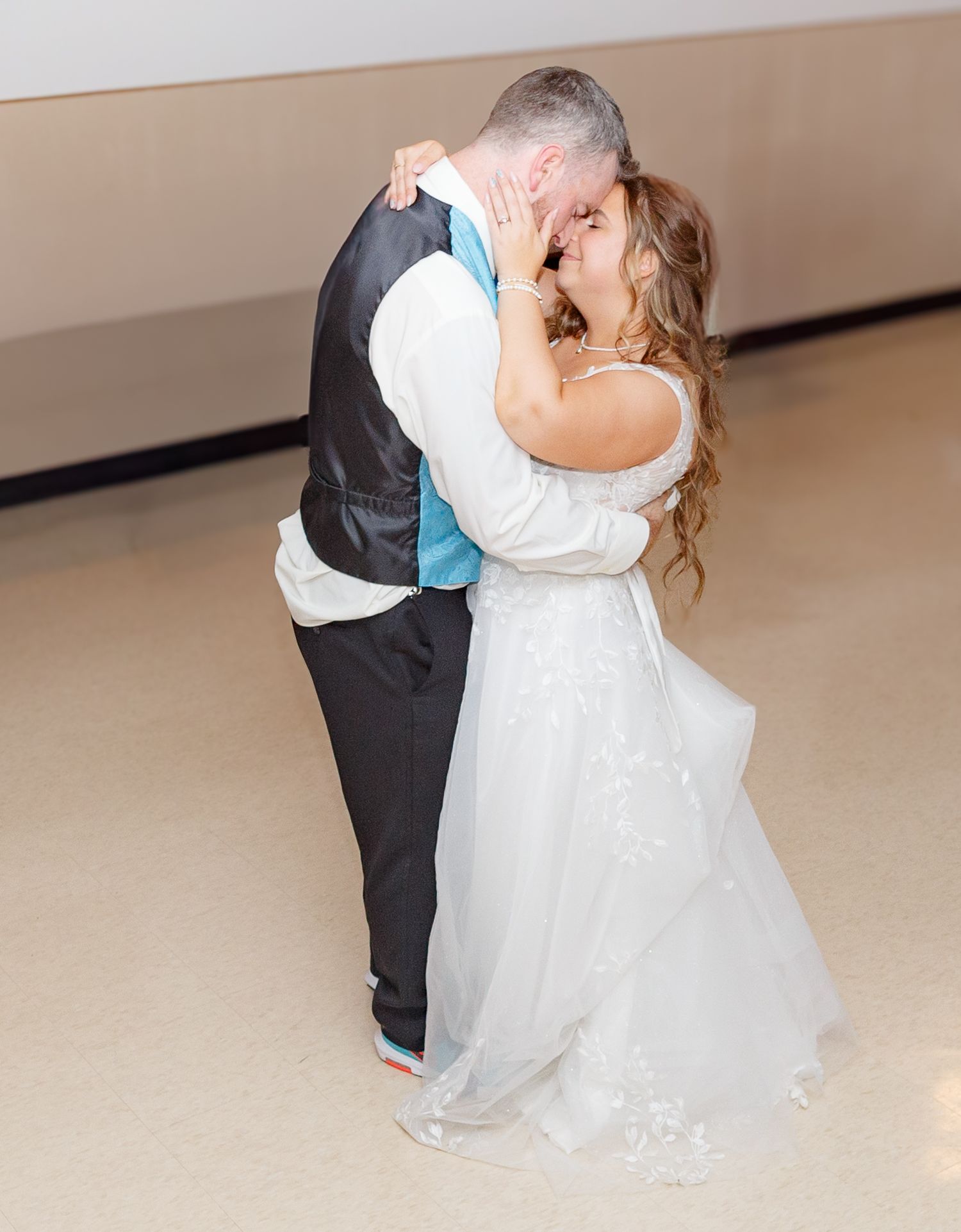 Wedding couple sharing an intimate dance moment on a light colored floor.