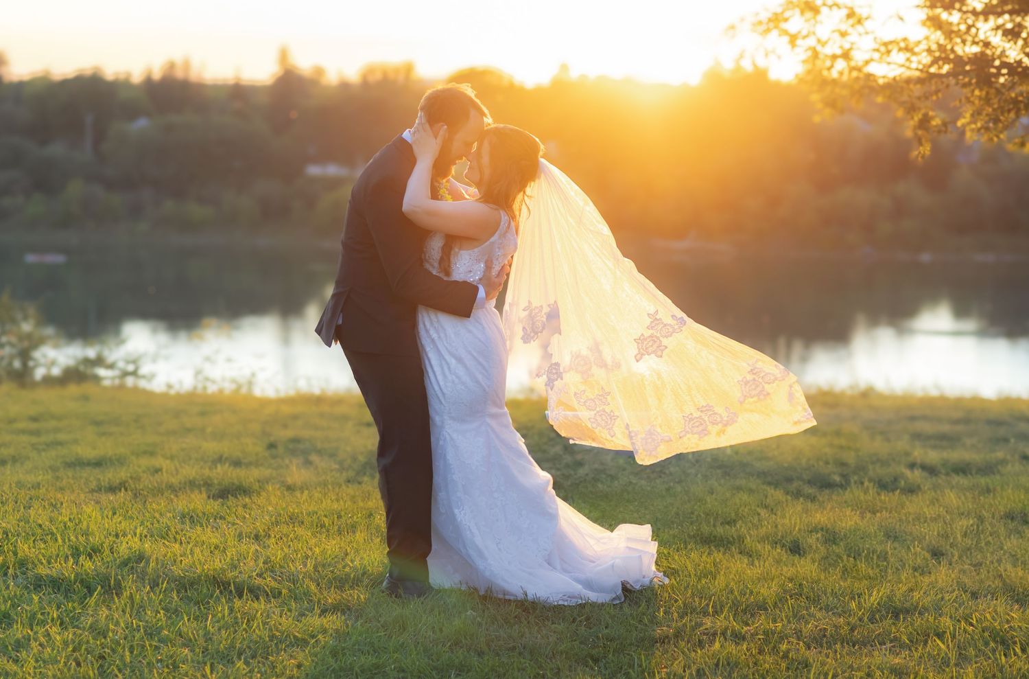 Romantic sunset wedding photos by a lake with golden light filtering through.
