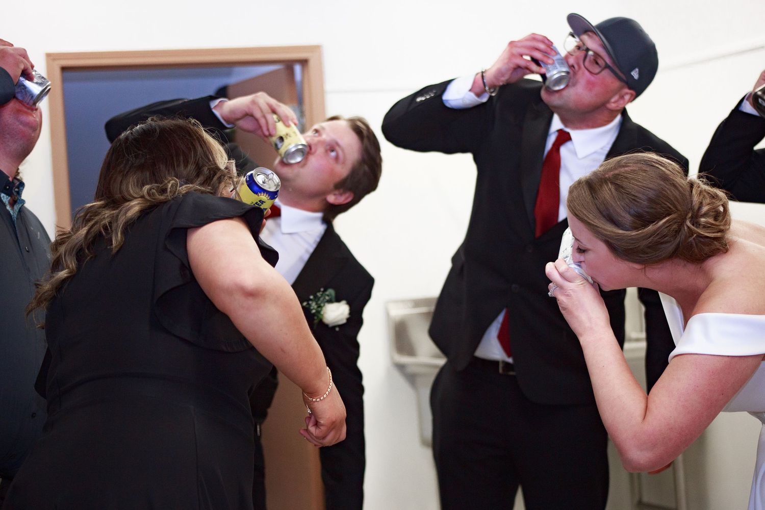 Wedding party members share celebratory drinks and toasts during reception festivities.